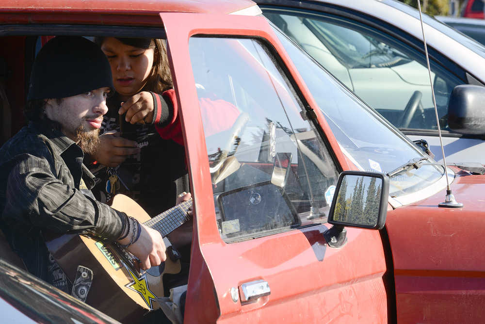 Photo by Rashah McChesney/Peninsula Clarion  Brad Altman, 19, of Kasilof, plays guitar in the parking lot of Soldotna High School Thursday Sept. 25, 2014 in Soldotna, Alaska.