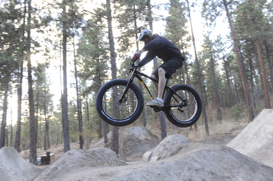 In this Oct. 21, 2014 photo, Ruk Kuchenbecker takes some jumps at the Beacon Hill jumps at Camp Sekani, in Spokane, Wash. The fat bike - a seemingly typical mountain bike frame with tires ranging from 3.7 to 4.8 inches wide - owes its origin to Fairbanks, Alaska. (AP Photo/The Spokesman-Review, Jesse Tinsley)