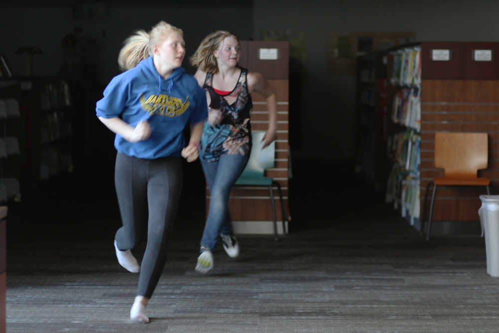 Ben Boettger/Peninsula Clarion Wary of zombies, humans Elizabeth Lisenby (front) and Nyia Peters (back) scurry across an open area during a round of Humans versus Zombies at the Soldotna Public Library on Friday, July 24.