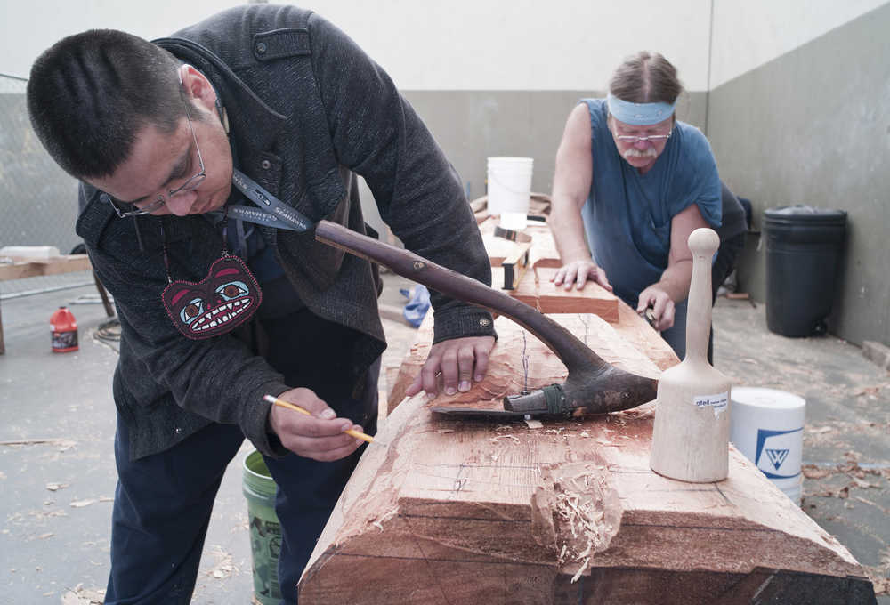 ADVANCE FOR THE WEEKEND OF JULY 2-3 AND THEREAFTER - In a Wednesday, June 22, 2016 photo, Sam Sheakley, left, and Fred Fulmer work on a 25-foot Raven totem pole at Harborview Elementary School in Juneau, Alaska. The 25-foot Raven pole is being designed by Nathan Jackson of Ketchikan and will be installed in front of Gastineau Elementary School when finished. It's one of two healing totems meant to acknowledge atrocities that took place on Douglas Island to the Aak'w Kwáan and T'aaku Kwáan, people who've lived in this area for thousands of years.  (Michael Penn/Juneau Empire via AP) MANDATORY CREDIT