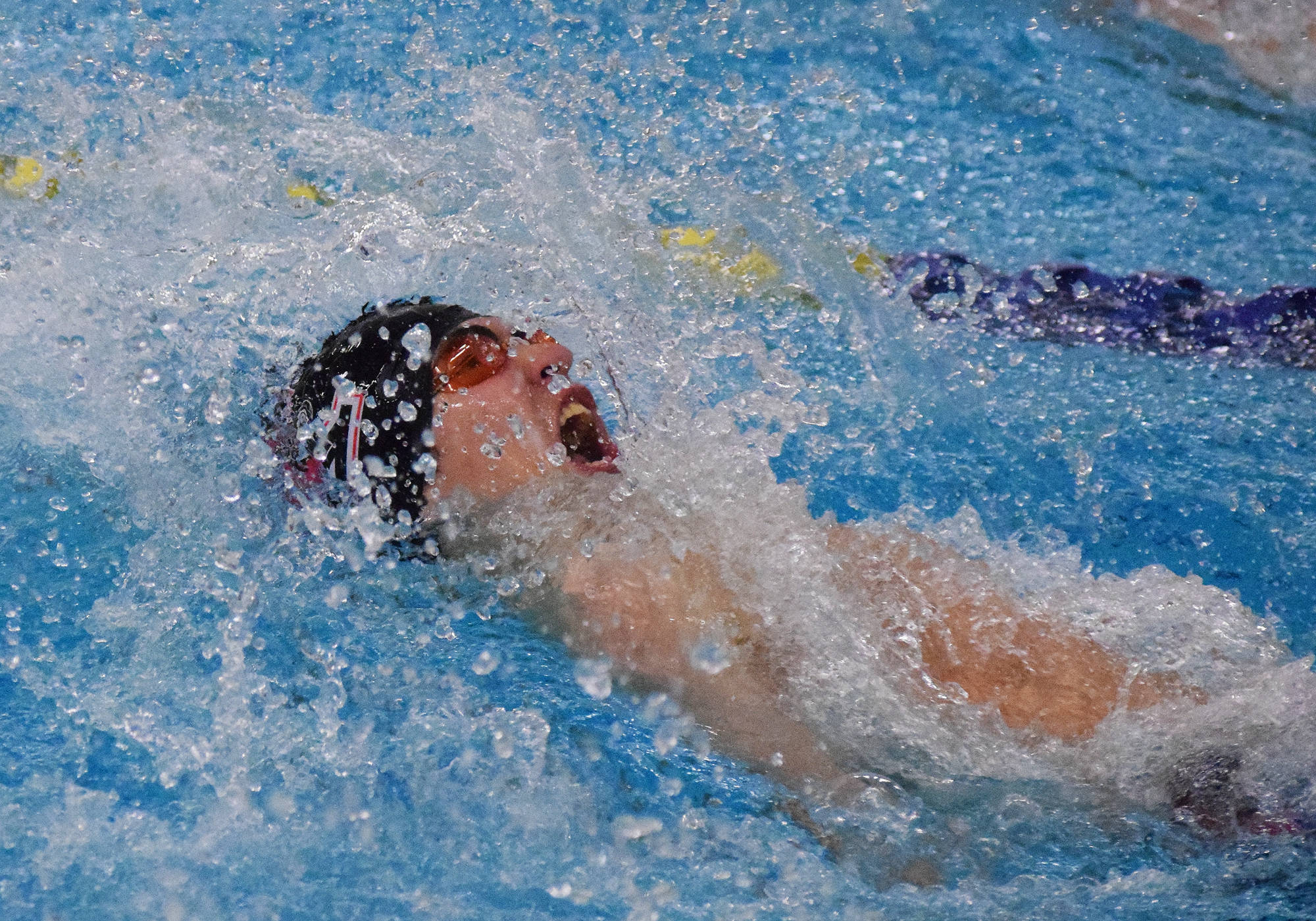 Kenai Central’s Savaii Heaven races to the third-place finish in the boys 100-yard backstroke Nov. 4, 2017, at the ASAA First National Bank State Swimming & Diving Championships at the Bartlett High pool. (Photo by Joey Klecka/Peninsula Clarion)