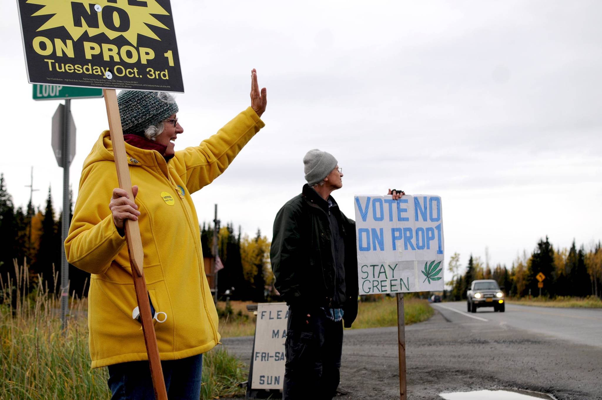 Ann Fraser (left) and Steve Waldron (right), both of Kasilof) wave signs opposing Kenai Peninsula Borough Proposition 1 on the corner of Pollard Loop and the Sterling Highway on Tuesday, Oct. 3, 2017 in Kasilof, Alaska. Voters in Kasilof and the other unincorporated communities of the borough voted Tuesday on Proposition 1, which asked whether commercial cannabis operations should be legal in the borough ouside the city limits. (Photo by Elizabeth Earl/Peninsula Clarion)