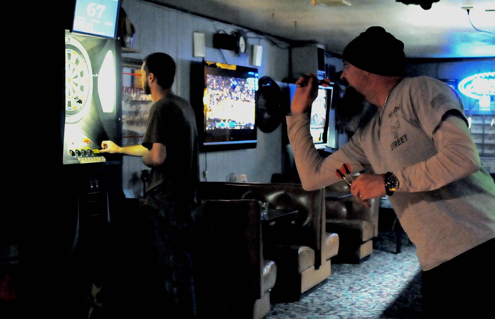 Travis Burnett (right) takes a shot with a dart at The Place Bar and Motel on Wednesday, Nov. 8, 2017 near Nikiski, Alaska. Burnett is part of a team that shoots darts at various bars around the central Kenai Peninsula, with his team headquartered at the Main Street Tap and Grill in Kenai. They rotate around other bars on an every-other-week basis. (Photo by Elizabeth Earl/Peninsula Clarion)