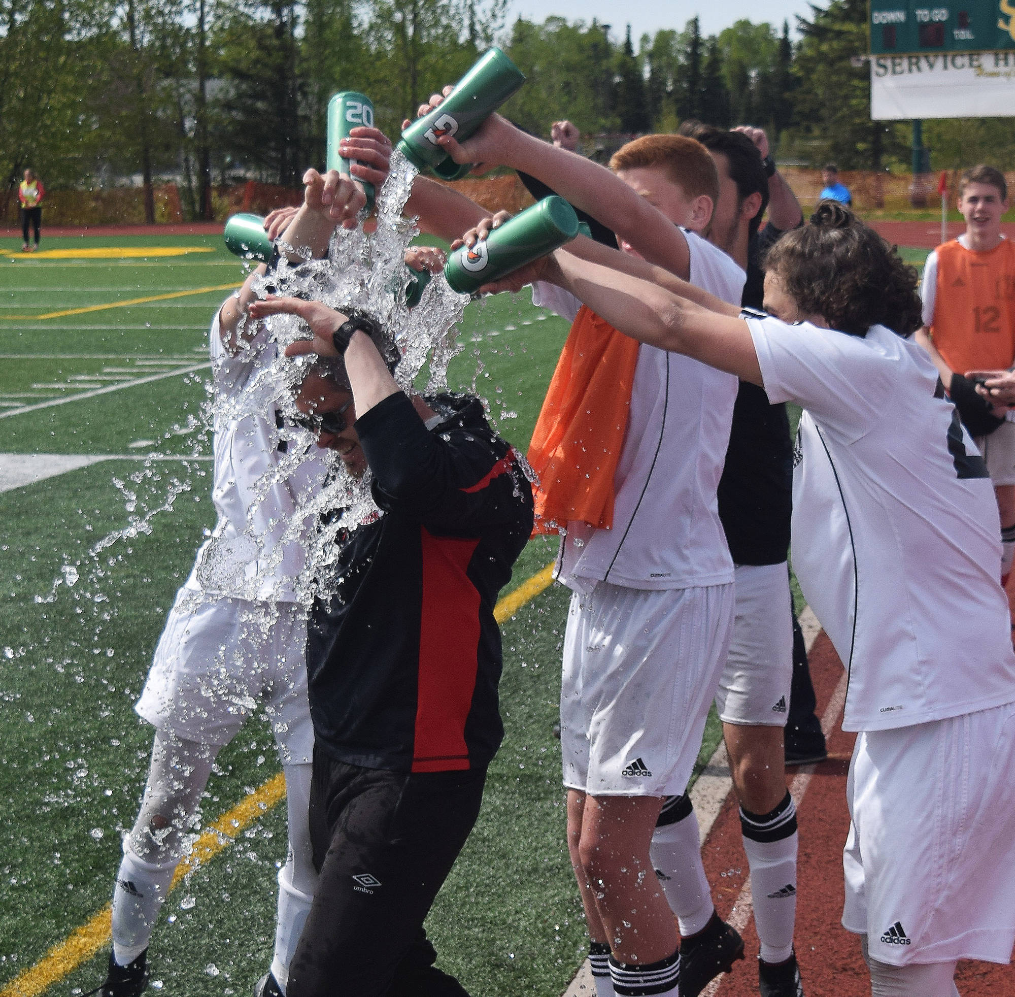 The Kenai Central boys celebrate winning the Division II state soccer championship by dousing head coach Joel Reemtsma in water Saturday afternoon at Service High School. (Photo by Joey Klecka/Peninsula Clarion)