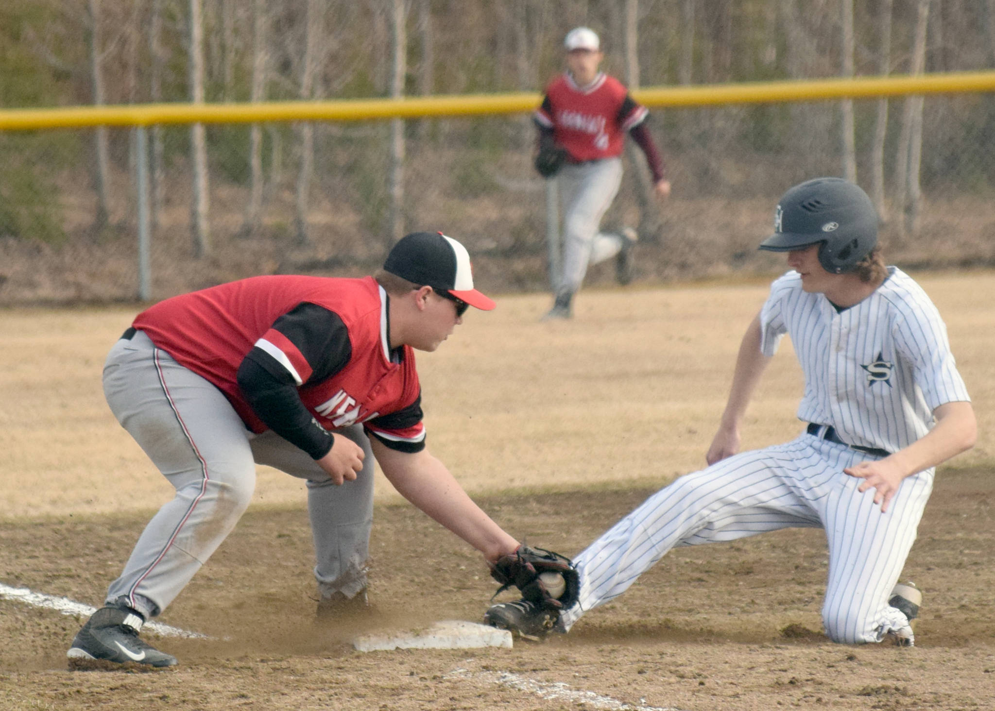 Soldotna’s Davey Belger slides under the tag of Kenai Central’s Ben Spinka on Tuesday, April 30, 2019, at the Soldotna Little League fields in Soldotna, Alaska. (Photo by Jeff Helminiak/Peninsula Clarion)