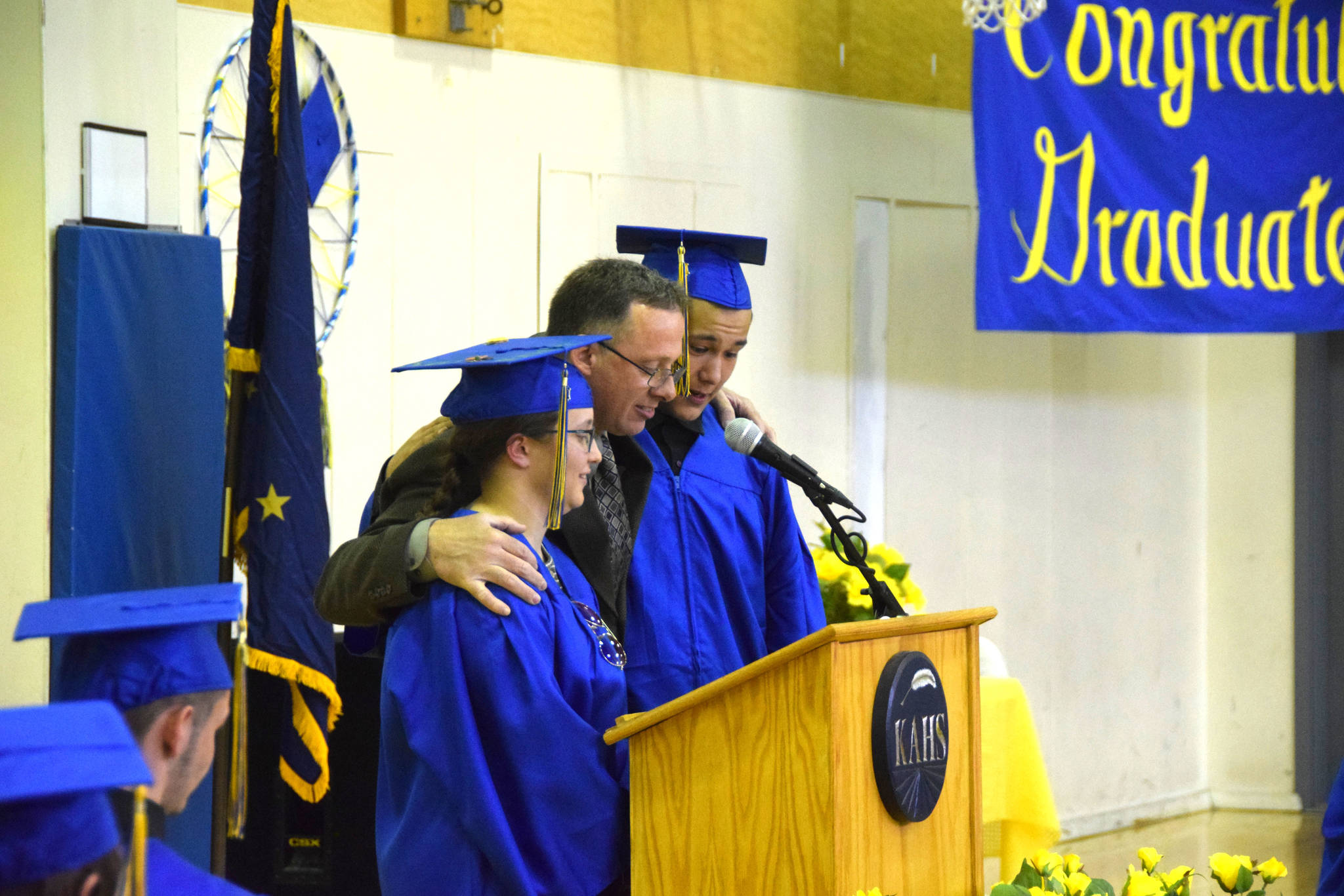 Hope Hoadley, left, Principal Loren Reese, center, and Collins Fleming, Jr, right, announce the turning of the tassels during the Kenai Alternative High School 2019 graduation in Kenai, Alaska on May 22, 2019. (Photo by Brian Mazurek/Peninsula Clarion)