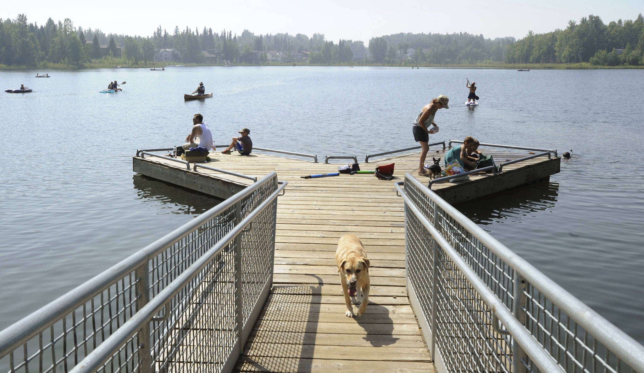 People with their dogs swarm to DeLong Lake hoping to stay cool in the record breaking heat in Anchorage, Alaska, Friday, July 5, 2019. Alaskans who routinely pack knit caps and fleece jackets in summer on Friday were swapping them for sunscreen and parasols amid a prolonged heatwave. Residents of Anchorage and other south-central cities completed a fifth week of above-normal temperatures, including a record high 90 degrees (32.22 Celsius) on Thursday, July 4, in the state’s largest city. (Anne Raup/Anchorage Daily News via AP)