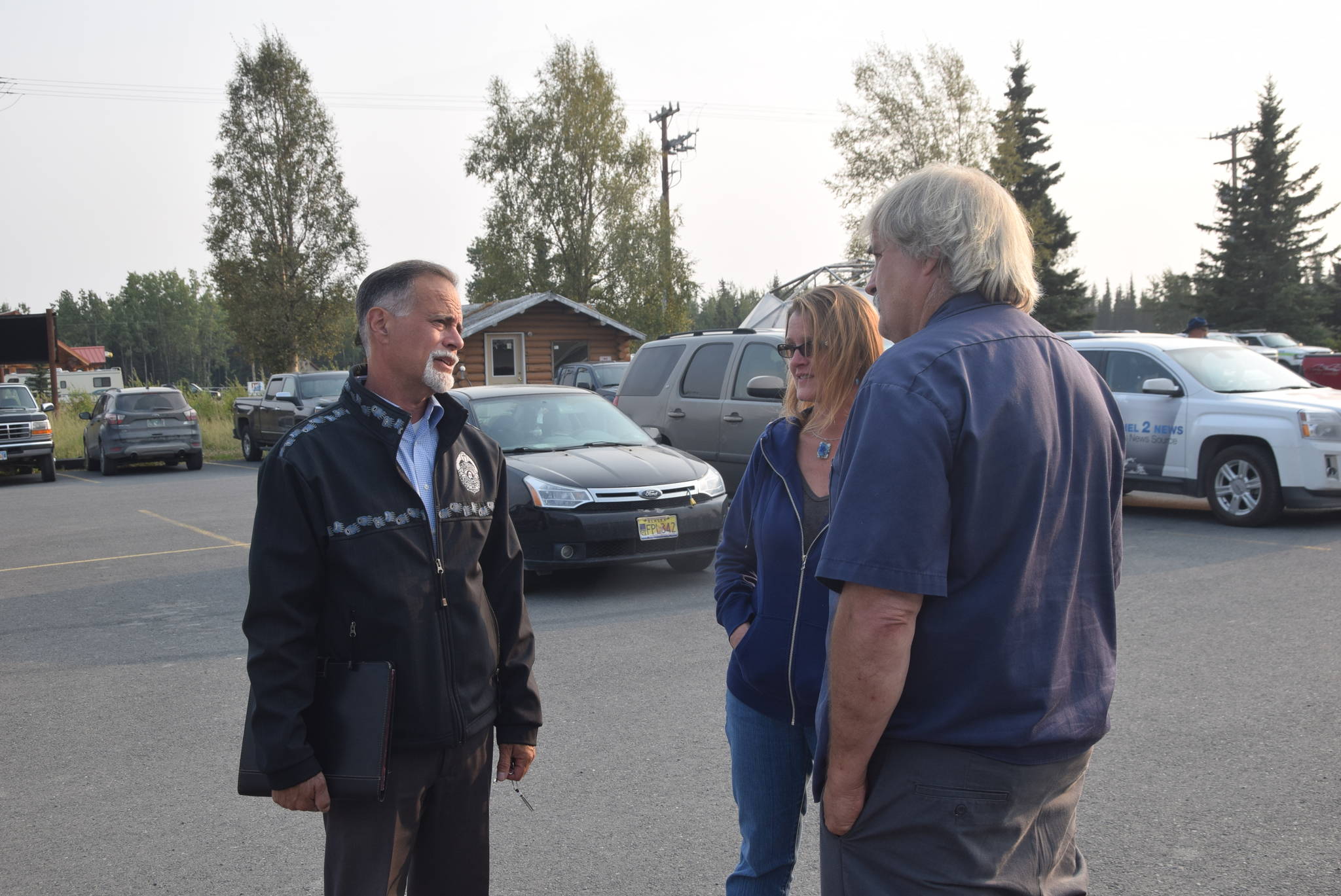 Sen. Peter Micciche, R-Soldotna, left, speaks to concerned residents about the Swan Lake Fire outside the Sterling Community Center in Sterling, Alaska on Aug. 22, 2019. (Photo by Brian Mazurek/Peninsula Clarion)