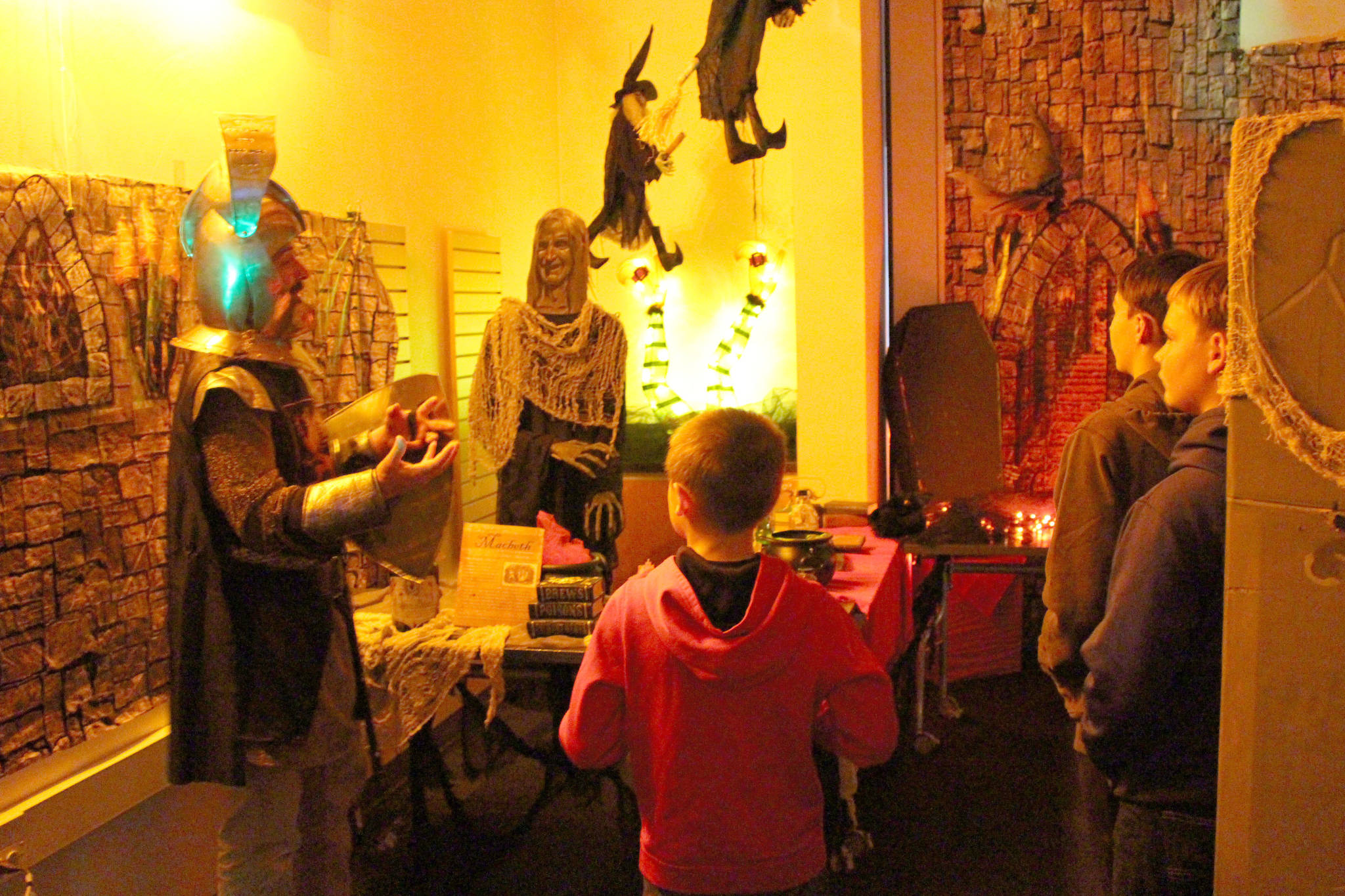 “Sir” James Adcox, left, leads Silas Barnes, Manoah Barnes and Nehemiah Barnes through the Literary Haunted House at the Kenai Community Library on Oct. 30, 2019. (Photo by Brian Mazurek/Peninsula Clarion)