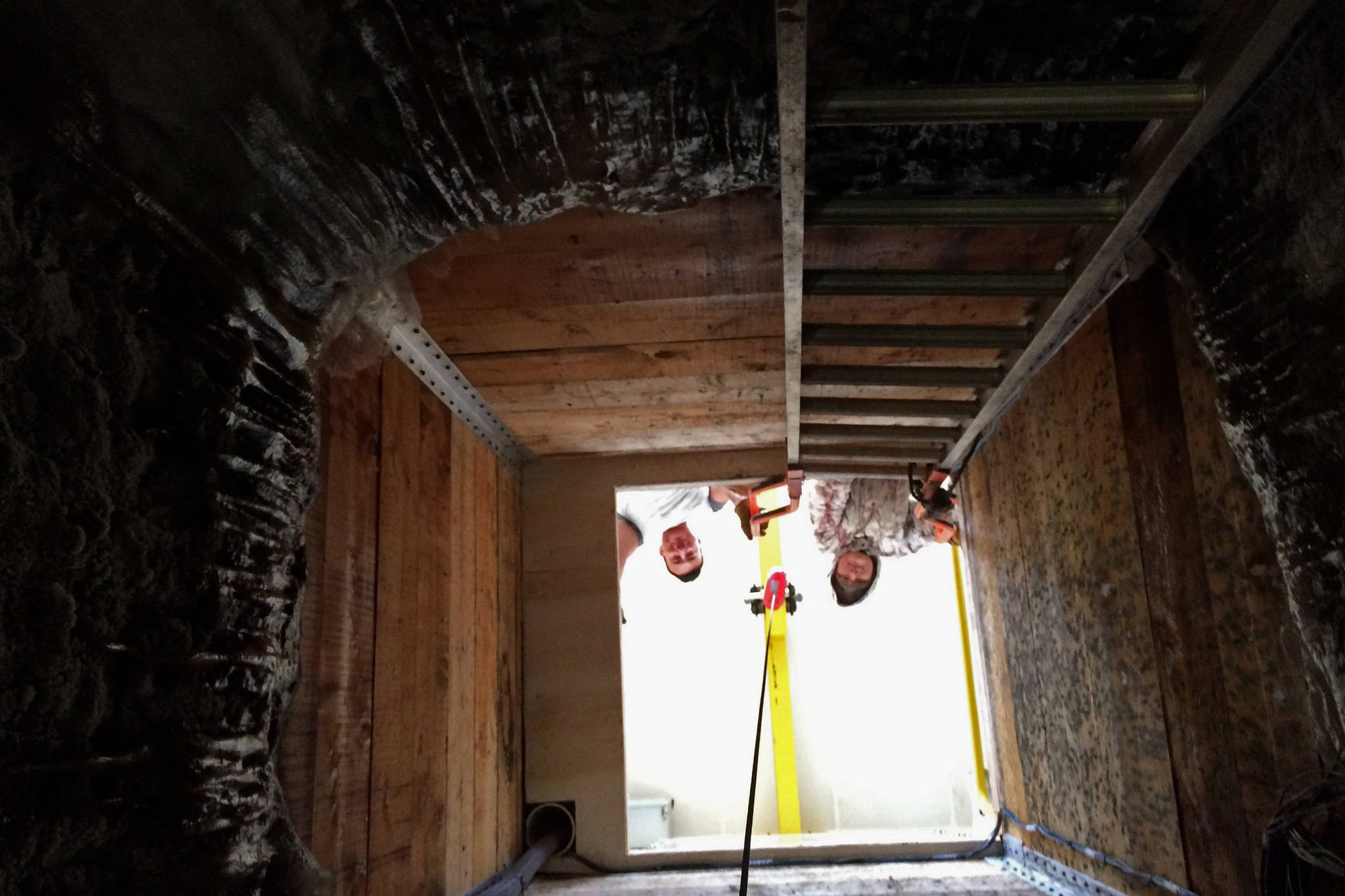 In this undated photo, two men look down a shaft in Kaktovik, Alaska, leading to a new community ice cellar, a type of underground food cache dug into the permafrost to provide natural refrigeration used for generations in far-north communities. Naturally cooled underground ice cellars, used in Alaska Native communities for generations, are becoming increasingly unreliable as a warming climate and other factors touch multiple facets of life in the far north. (Marnie Isaacs/Kaktovik Community Foundation via AP)