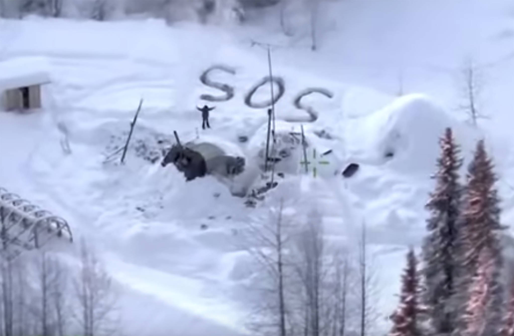 In this image made from video released by the Alaska State Troopers, an aerial helicopter view from Jan. 9, 2020, shows a man waving with distress signal “S.O.S.” outside Susitna Valley, Alaska. Alaska State Troopers have rescued Tyson Steele, 30, who survived in a makeshift shelter after his remote cabin burned last month. (Alaska State Troopers via AP)