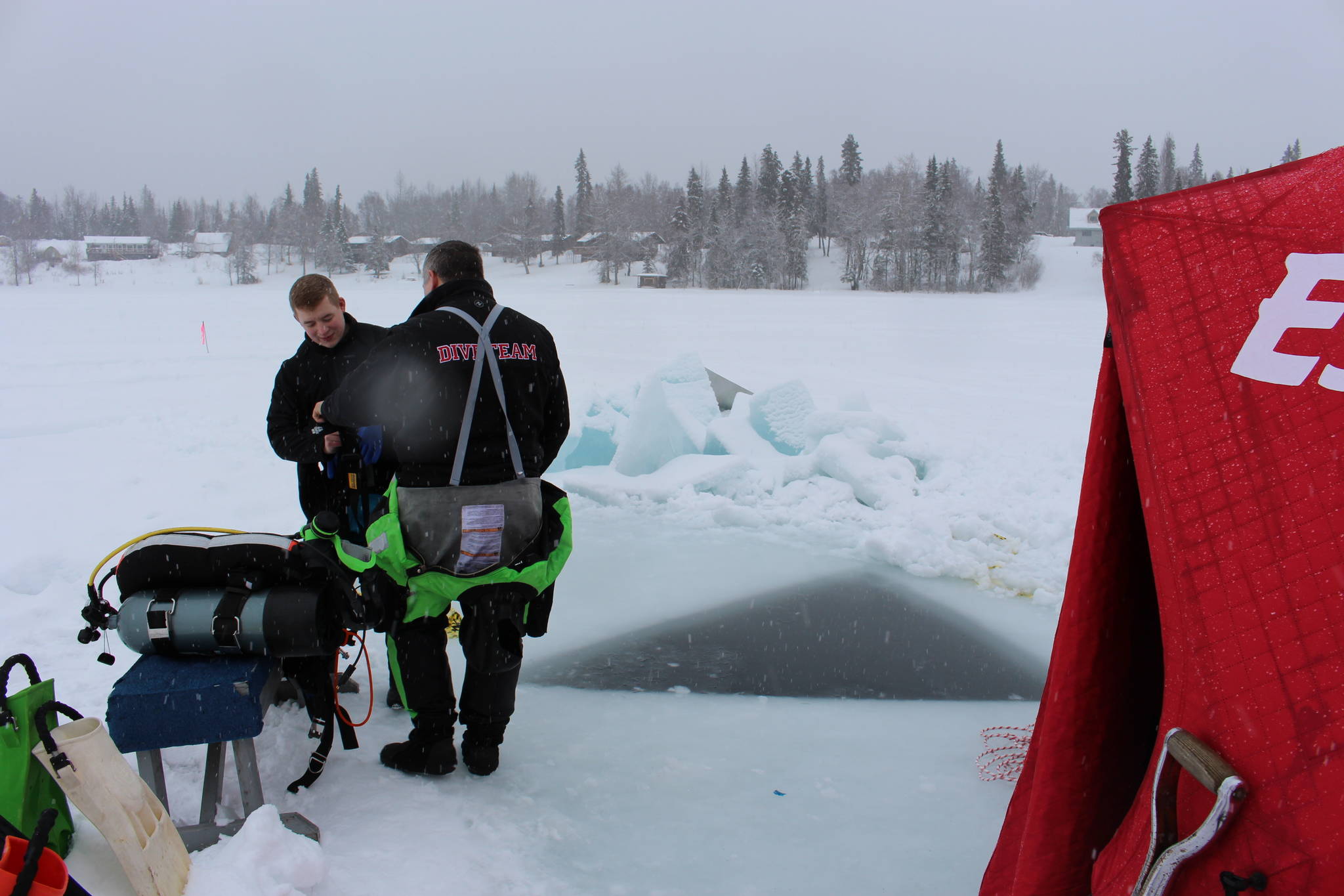 T.J. Cox, left, and Stephen Robertson, right, suit up for an ice dive on Island Lake in Nikiski, Alaska on March 21, 2020. (Photo by Brian Mazurek/Peninsula Clarion)