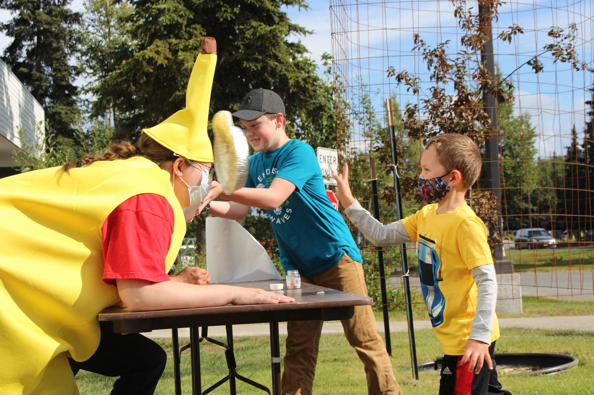 Liam McCloud, right, and Josh Bolling, center, throw pies in the faces of Kenai Librarians Bethany McMilin, left, and James Adcox outside the Kenai Library on Aug. 19, 2020. McCloud and Bolling won the right to throw the pies for participating in the library’s summer reading program, which went virtual this year. (Photo by Brian Mazurek/Peninsula Clarion)