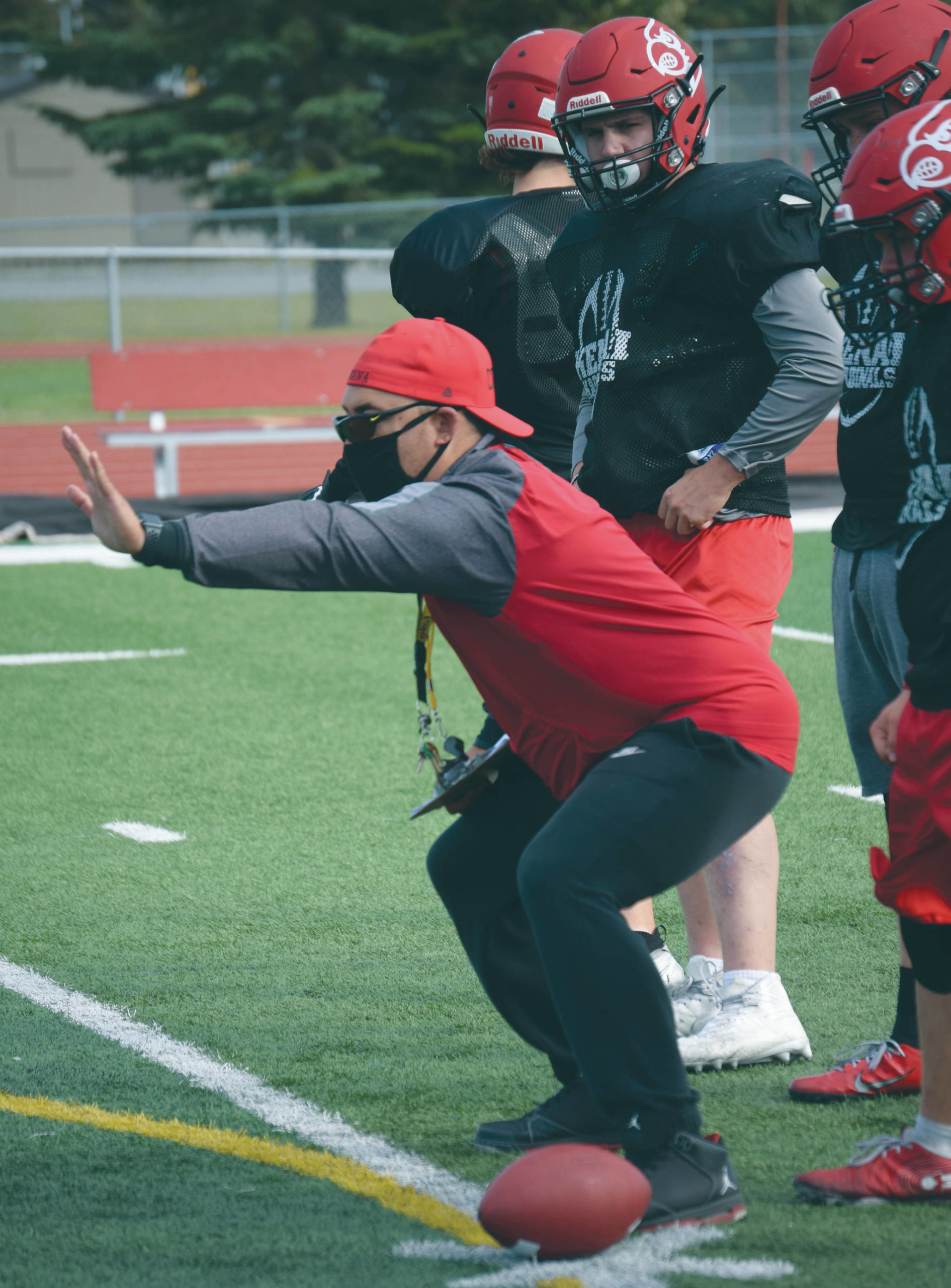 Kenai Central football coach Travis Akana coaches blocking technique as Jackson DuPerron looks on during practice Monday, Aug. 31, 2020, at Ed Hollier Field at Kenai Central High School in Kenai, Alaska. (Photo by Jeff Helminiak/Peninsula Clarion)