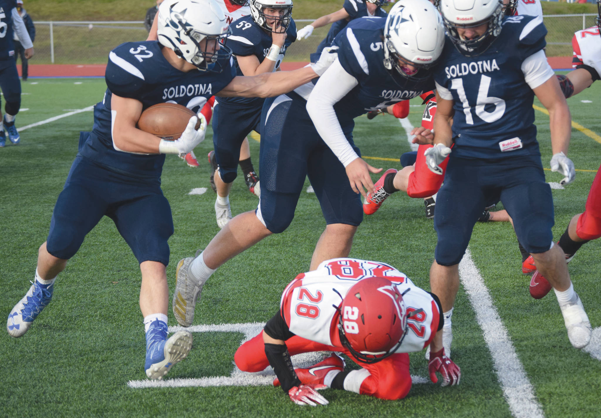 (Photo by Jeff Helminiak/Peninsula Clarion)Soldotna’s Dennis Taylor follows the blocking of Brock Wilson and Austin Escott past Kenai Central’s James Sparks on Friday, at Justin Maile Field in Soldotna.