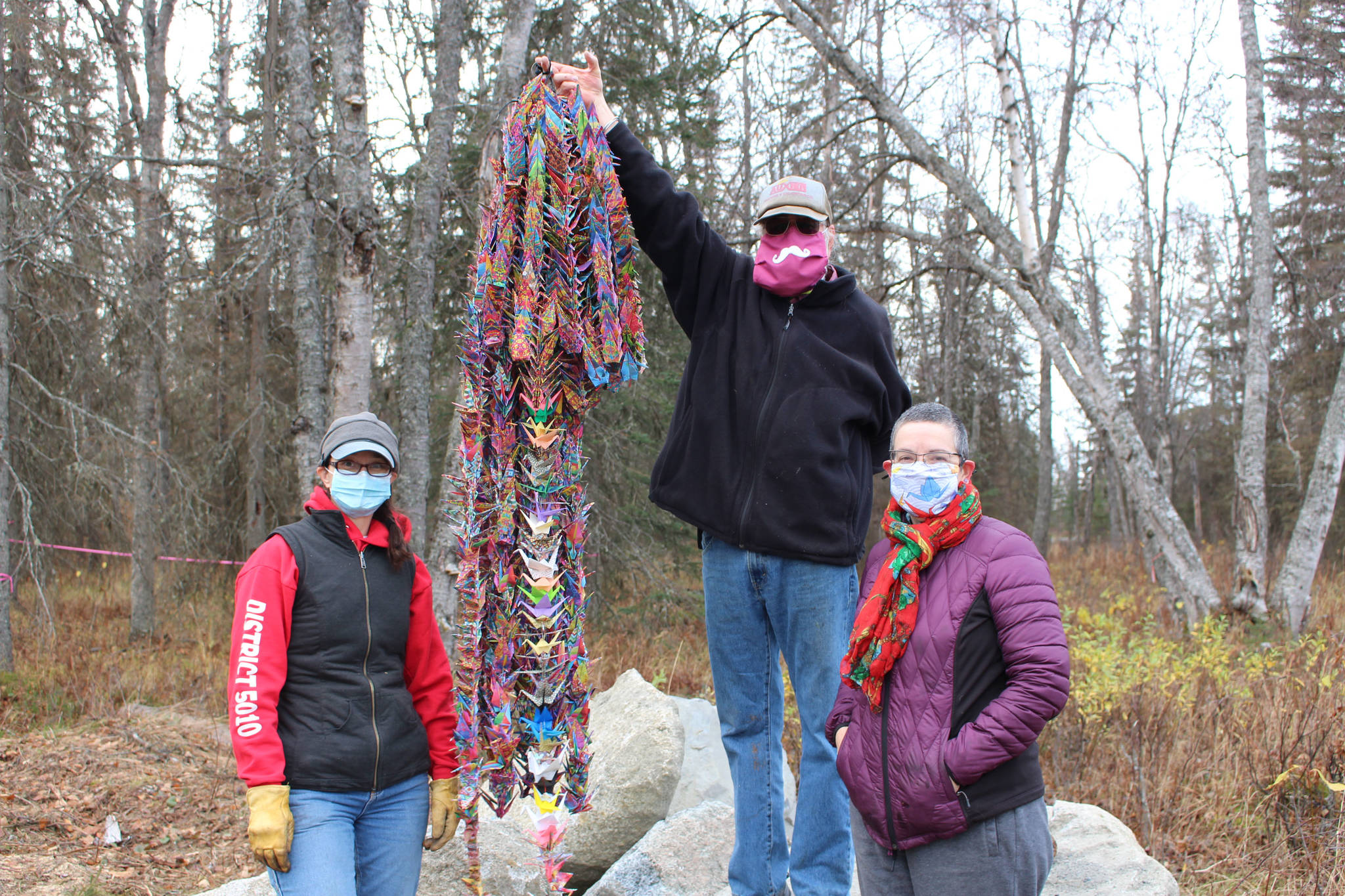 From left, Sarah Pyhala, president of the board for the Shimai Toshi Garden Trails, which is spearheading the Kenai Peninsula Peace Crane Garden Trail, Allan Auxier and Reverend Diane Dunn pose with a string of 1,000 origami cranes on Marydale Avenue in Soldotna, Alaska, on Oct. 17, 2020. Dunn, of Deer Island, Oregon, made the cranes . (Photo by Brian Mazurek/Peninsula Clarion)