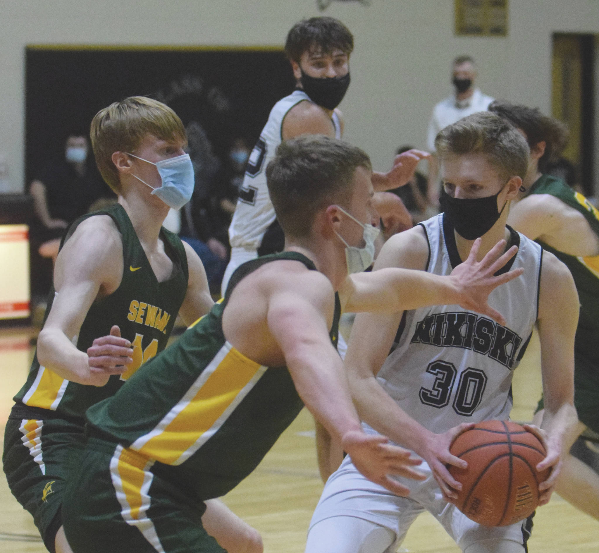 Nikiski’s Austin Stafford drives on Seward’s Max Pfeiffenberger and Trey Ingalls on Tuesday, Feb. 9, 2021, at Nikiski High School in Nikiski, Alaska. (Photo by Jeff Helminiak/Peninsula Clarion)