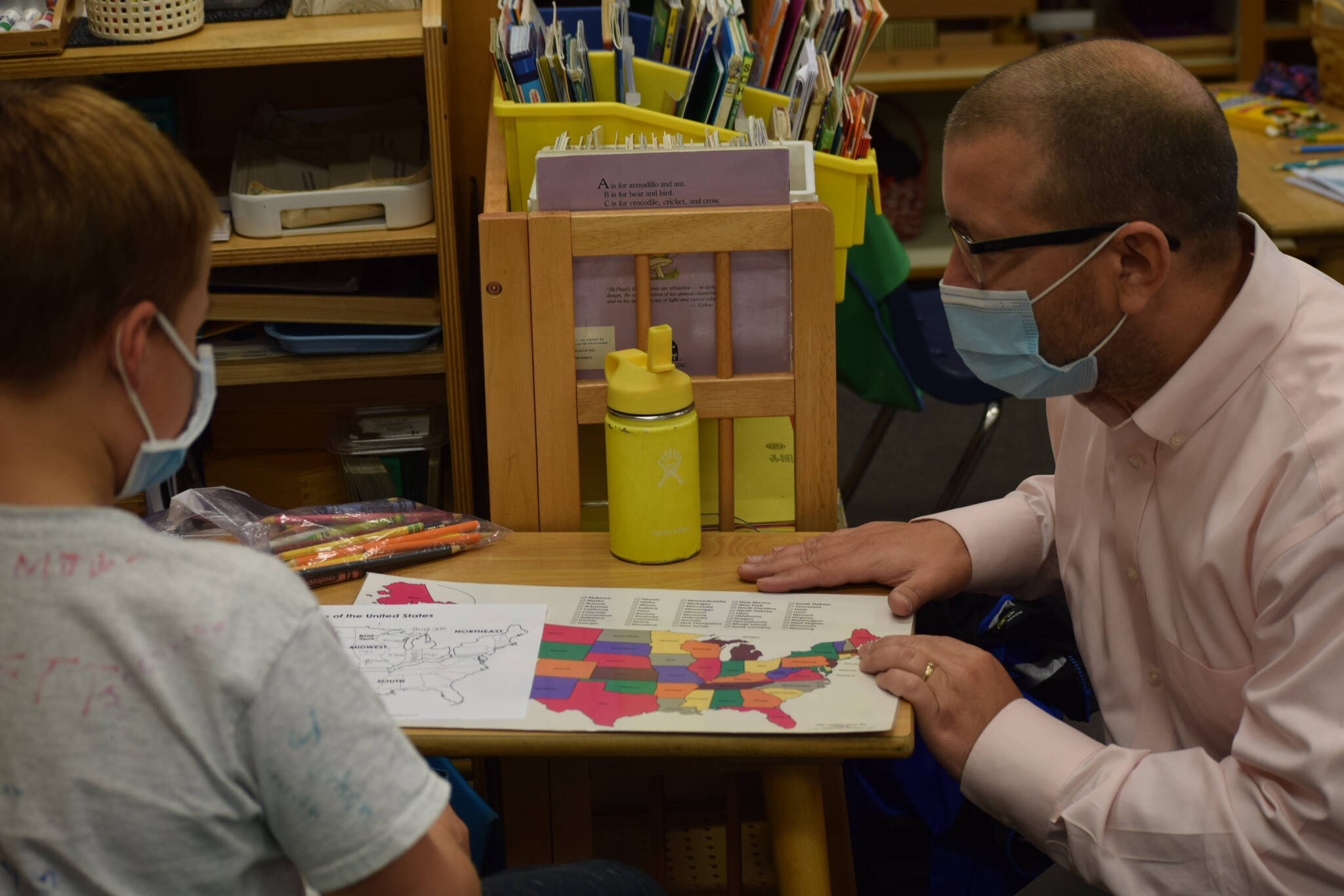 Everett Anderson, second grade, shows Principal John DeVolld some of his class work at Soldotna Montessori Charter School on Tuesday, Sept. 21, 2021. (Camille Botello/Peninsula Clarion)