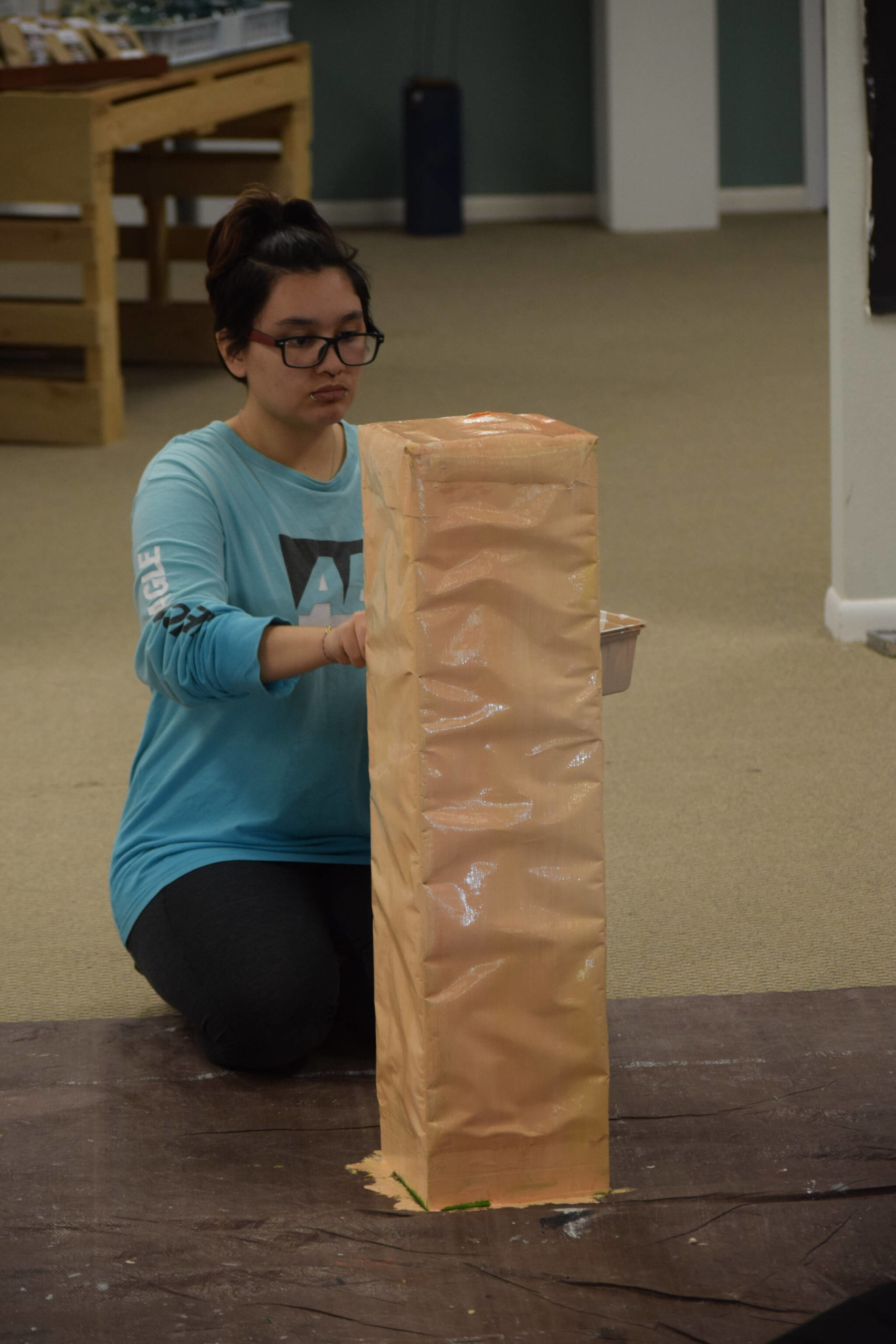 Emma Brown paints a podium for the Kenai Alternative High School’s mural installation at the Kenai Art Center on Tuesday, Nov. 9, 2021. (Camille Botello/Peninsula Clarion)