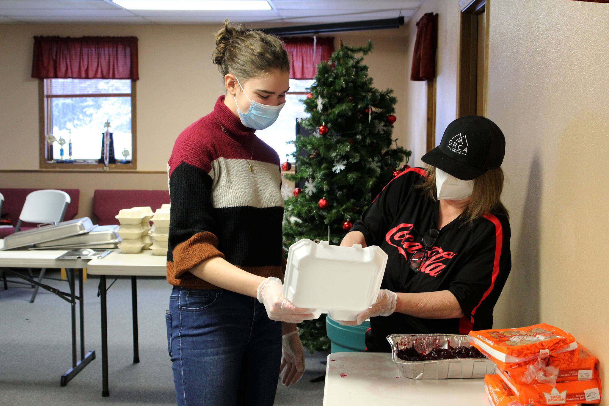 Kathy Heindl (right) loads cranberry sauce into a tray assembled by Regan Evans (left) at a drive-through Thanksgiving meal event hosted by the Salvation Army on Thursday, Nov. 25, 2021 in Kenai, Alaska. (Ashlyn O’Hara/Peninsula Clarion)