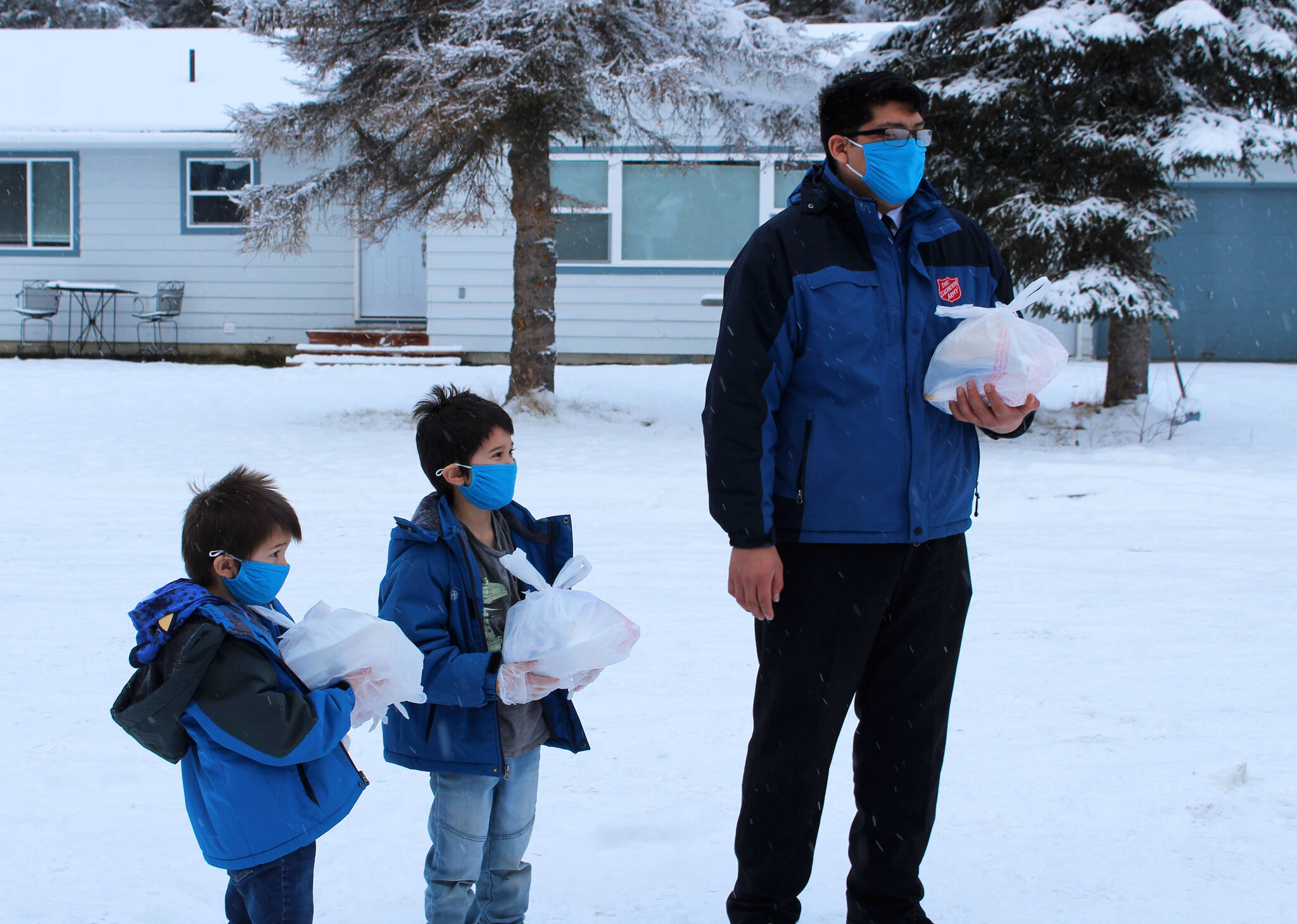 Carter Kyle (left), Lincoln Kyle (center) and Brandon Kyle (right) hand off Thanksgiving meals at a drive through event hosted by the Salvation Army on Thursday, Nov. 25, 2021 in Kenai, Alaska. (Ashlyn O’Hara/Peninsula Clarion)