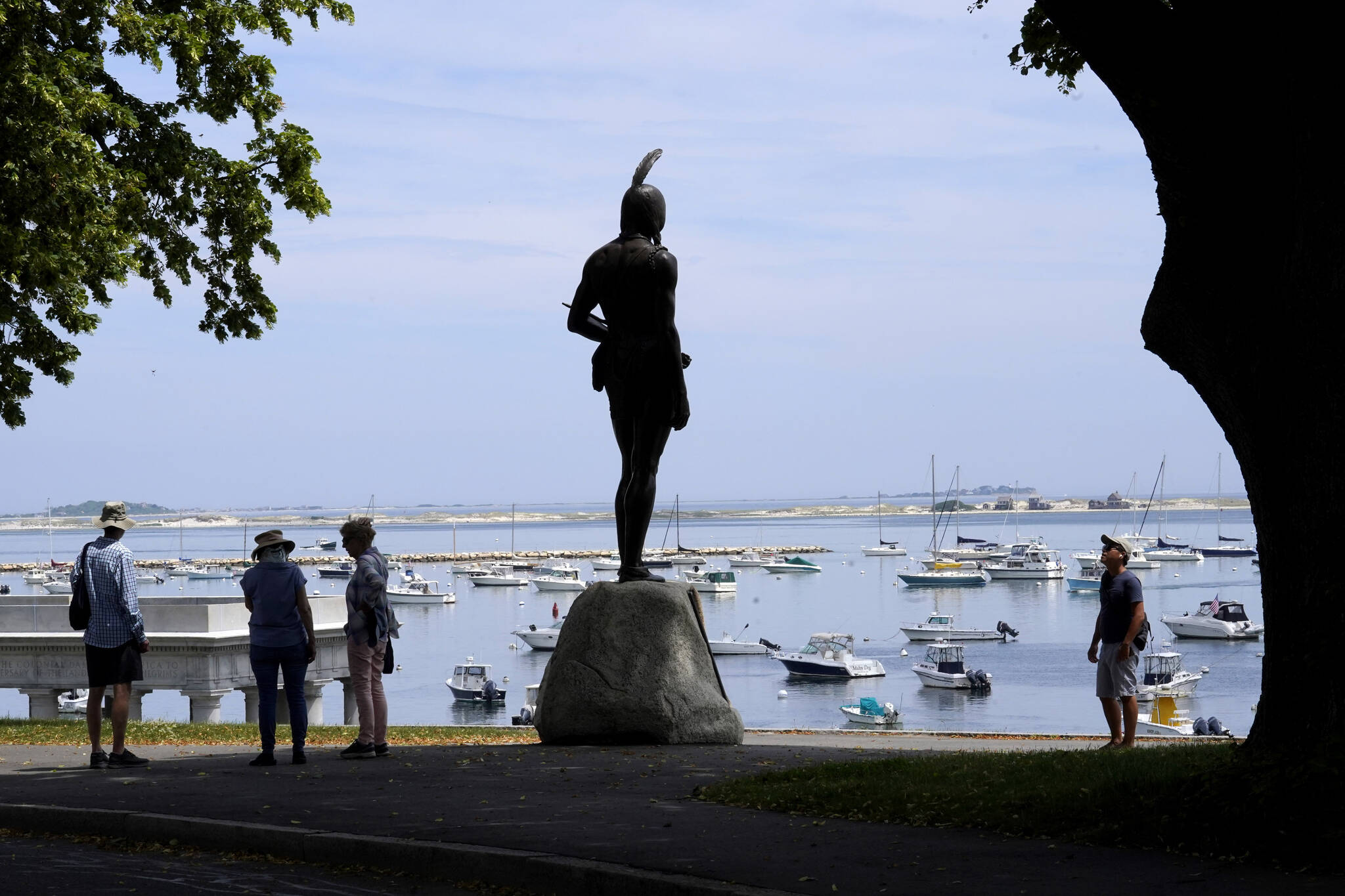 AP Photo / Steven Senne
Visitors stand near a 1921 statue of the Wampanoag leader Massasoit, center, June 9 on Cole’s Hill, in Plymouth, Mass. This year marks the 400th anniversary of the 1621 gathering between English settlers and Wampanoag people which the Thanksgiving holiday celebrates, but Indigenous people commemorate the holiday in a different way.