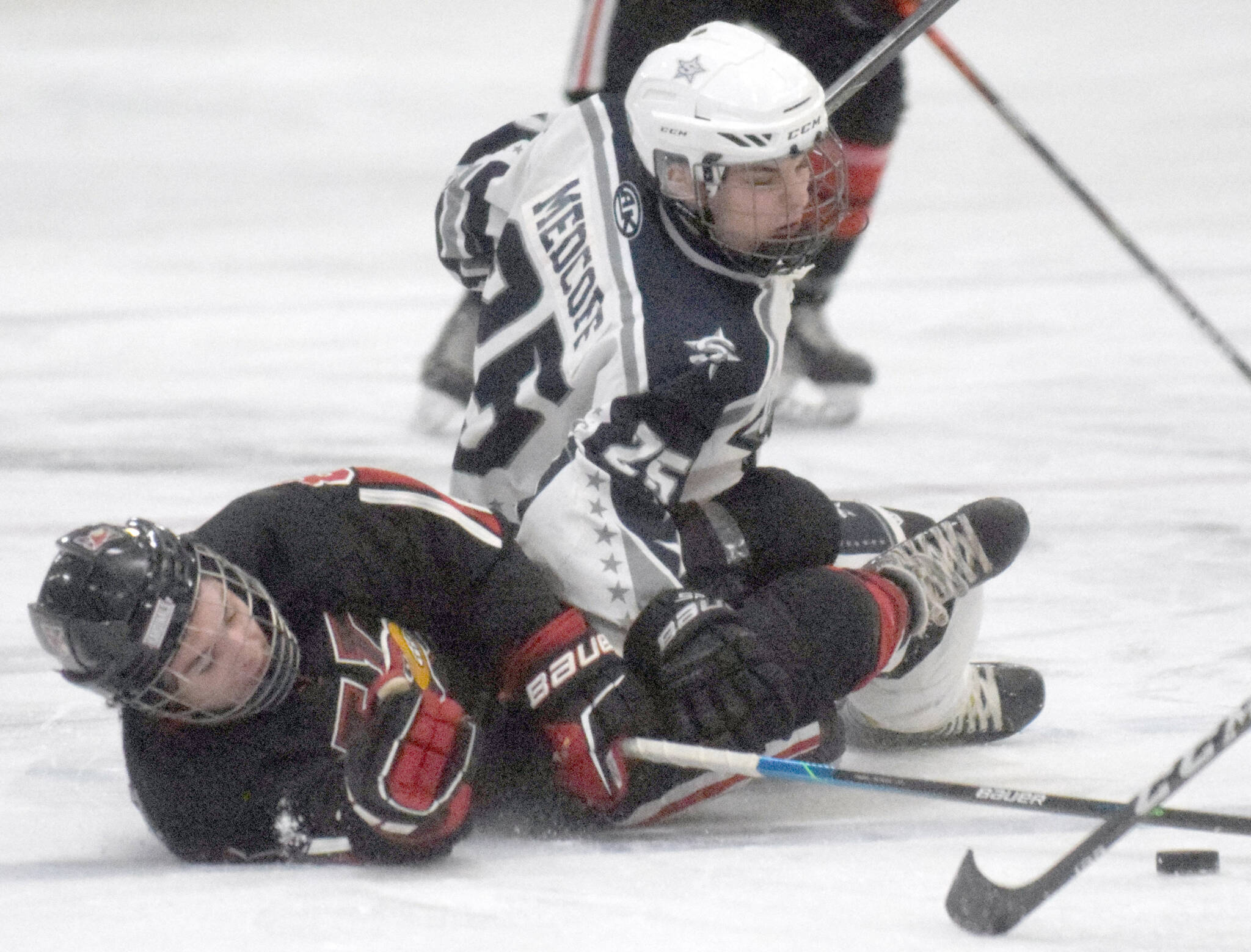 Kenai Central’s Koda Norbeck and Soldotna’s Gehret Medcoff battle for the puck Thursday, Jan. 27, 2022, at the Soldotna Regional Sports Complex in Soldotna, Alaska. (Photo by Jeff Helminiak/Peninsula Clarion)