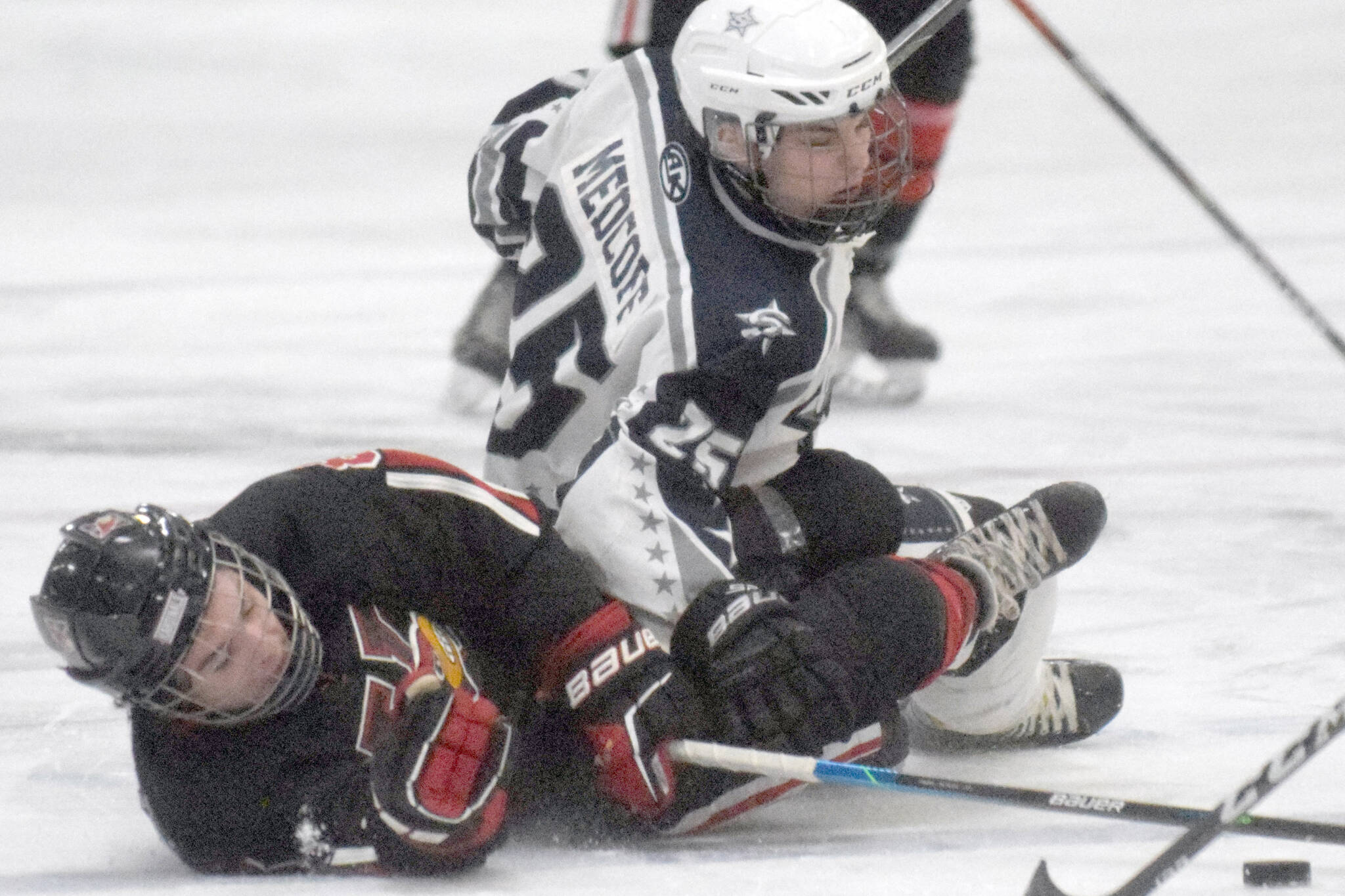 Kenai Central's Koda Norbeck and Soldotna's Gehret Medcoff battle for the puck Thursday, Jan. 27, 2022, at the Soldotna Regional Sports Complex in Soldotna, Alaska. (Photo by Jeff Helminiak/Peninsula Clarion)