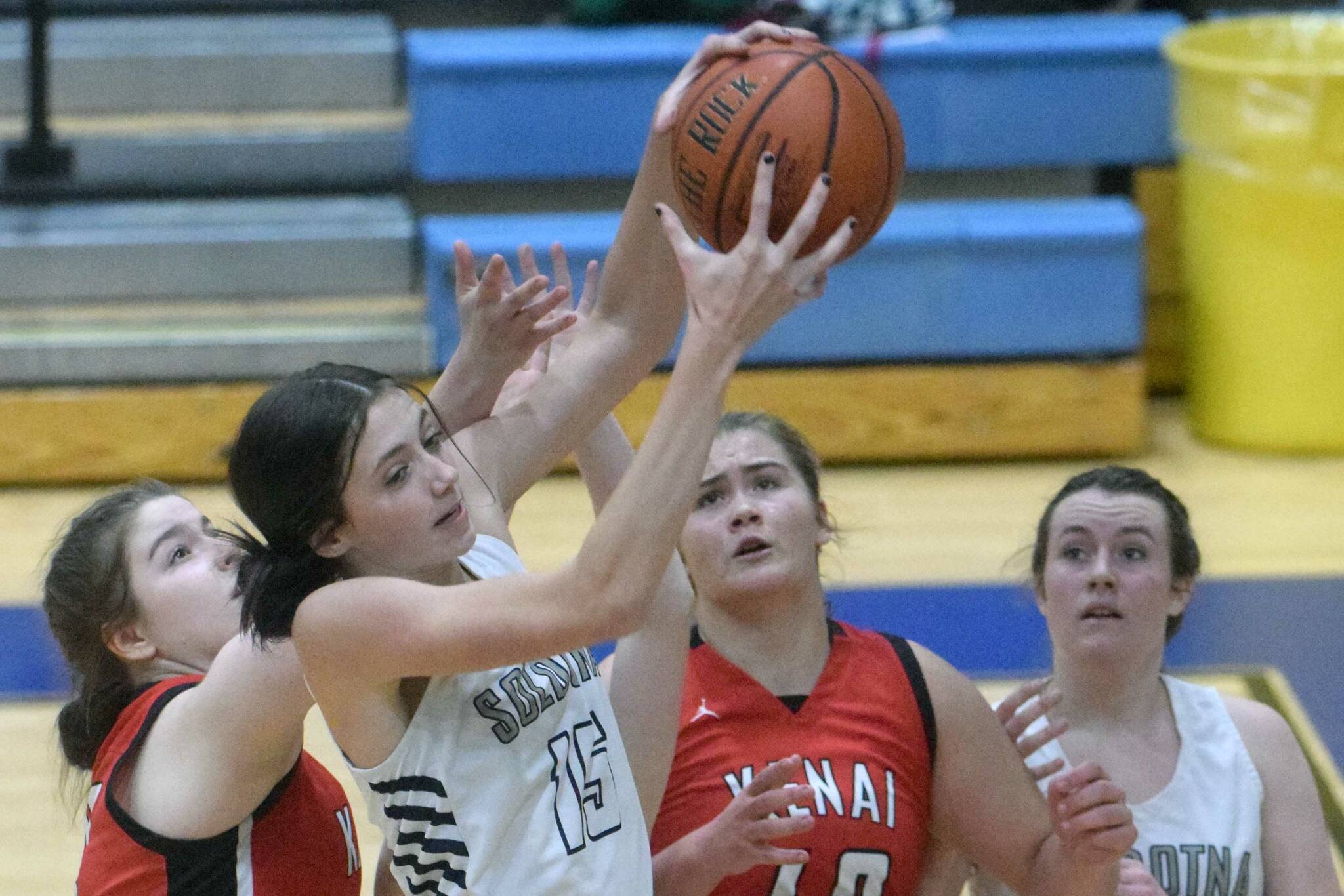 Soldotna's Adarra Hagelund grabs a rebound in front of Kenai's Denali Bernard and Emma Beck, and SoHi's Tanner Inman, at Soldotna High School on Friday, Jan. 28, 2022, in Soldotna, Alaska. (Photo by Jeff Helminiak/Peninsula Clarion)