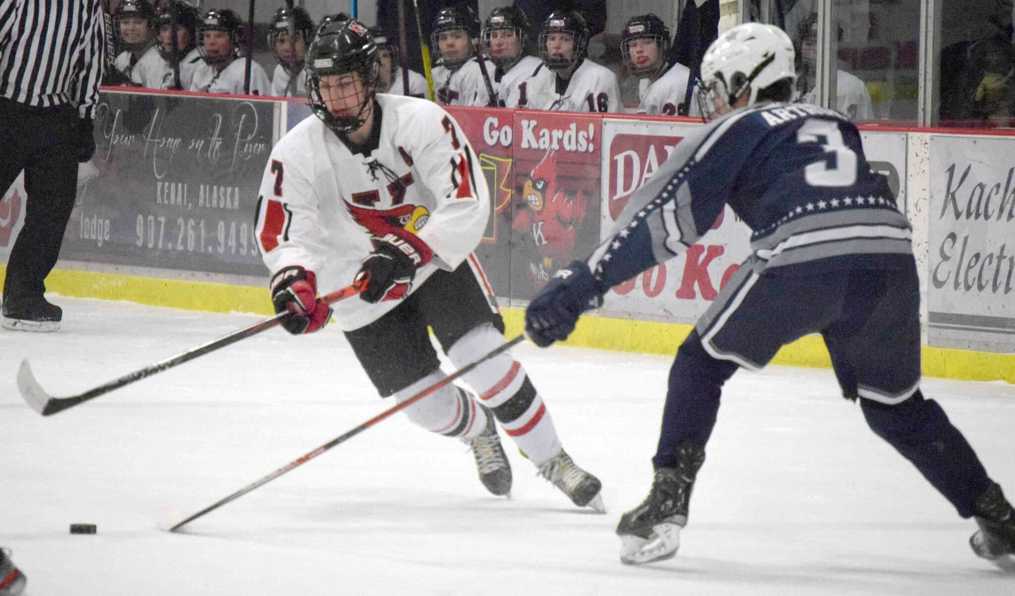 Kenai Central’s Jacob Begich carries the puck against Soldotna’s Andrew Arthur on Dec. 14, 2021, at the Kenai Multi-Purpose Facility in Kenai, Alaska. (Photo by Jeff Helminiak/Peninsula Clarion)