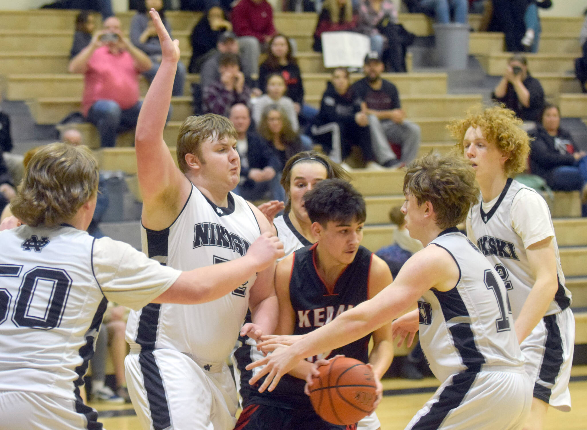 Kenai Central’s Jakob Kvasnikoff tries to escape the trap of Nikiski’s Drew Handley and Isaiah Daniels on Tuesday, Feb. 15, 2022, at Nikiski High School in Nikiski, Alaska. (Photo by Camille Botello/Peninsula Clarion)