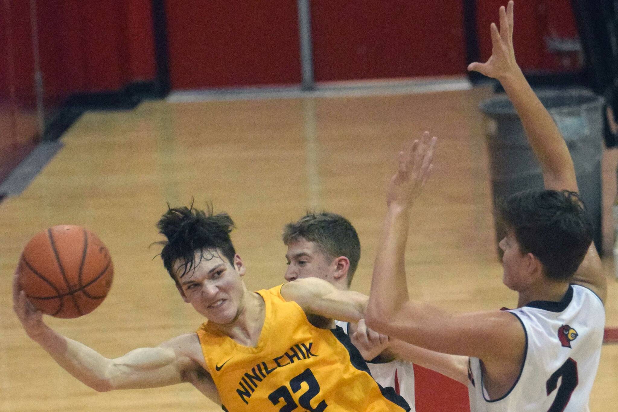 Ninilchik's Justin Trail saves the ball in front of Kenai Central's Luke Armstrong and Eli McCubbins on Saturday, March 5, 2022, at Kenai Central High School in Kenai, Alaska. (Photo by Jeff Helminiak/Peninsula Clarion)