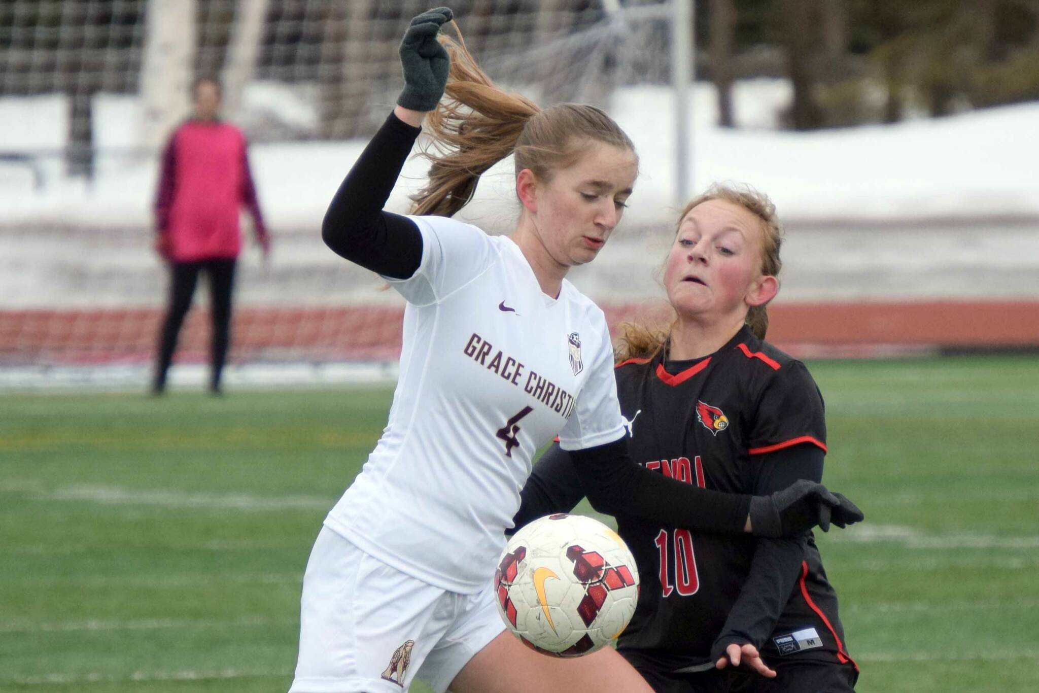 Grace Christian's Sophia Coverdell and Kenai Central's Kylie Verkuilen battle for the ball Friday, April 1, 2022, at Kenai Central high School in Kenai, Alaska. (Photo by Jeff Helminiak/Peninsula Clarion)