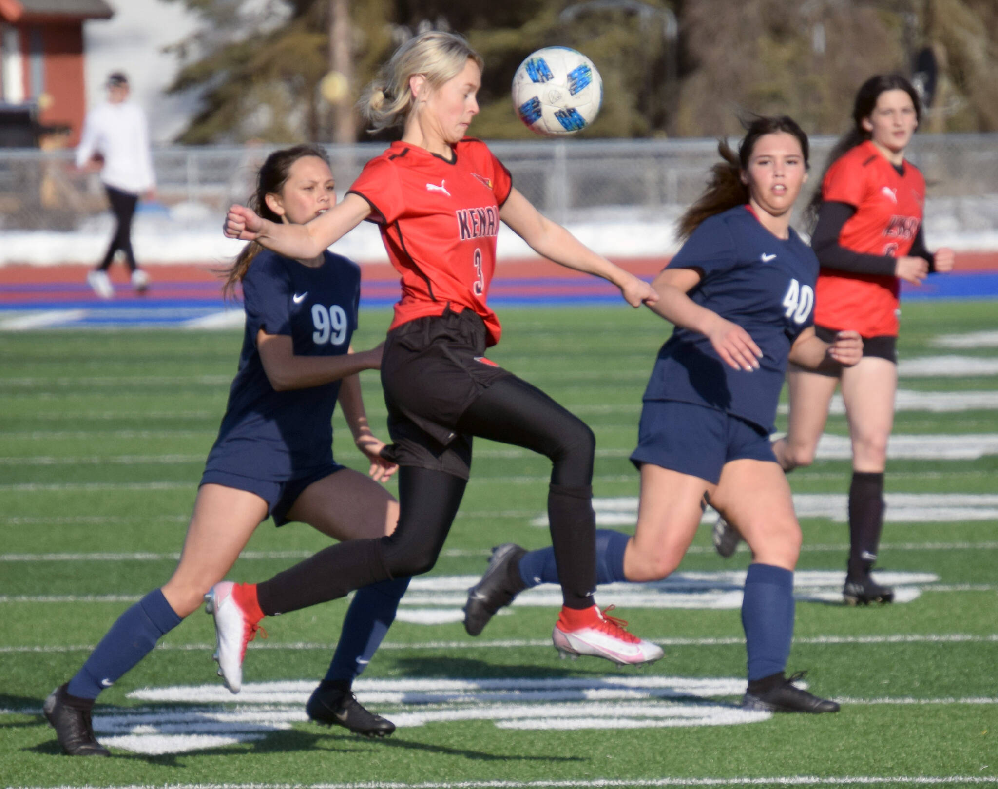 Kenai Central’s Cali Holmes tries to clear the ball from Soldotna’s Caleigh Glassmaker and Caylee Uribe-Koivisto on Thursday, April 14, 2022, at Soldotna High School in Soldotna, Alaska. (Photo by Jeff Helminiak/Peninsula Clarion)