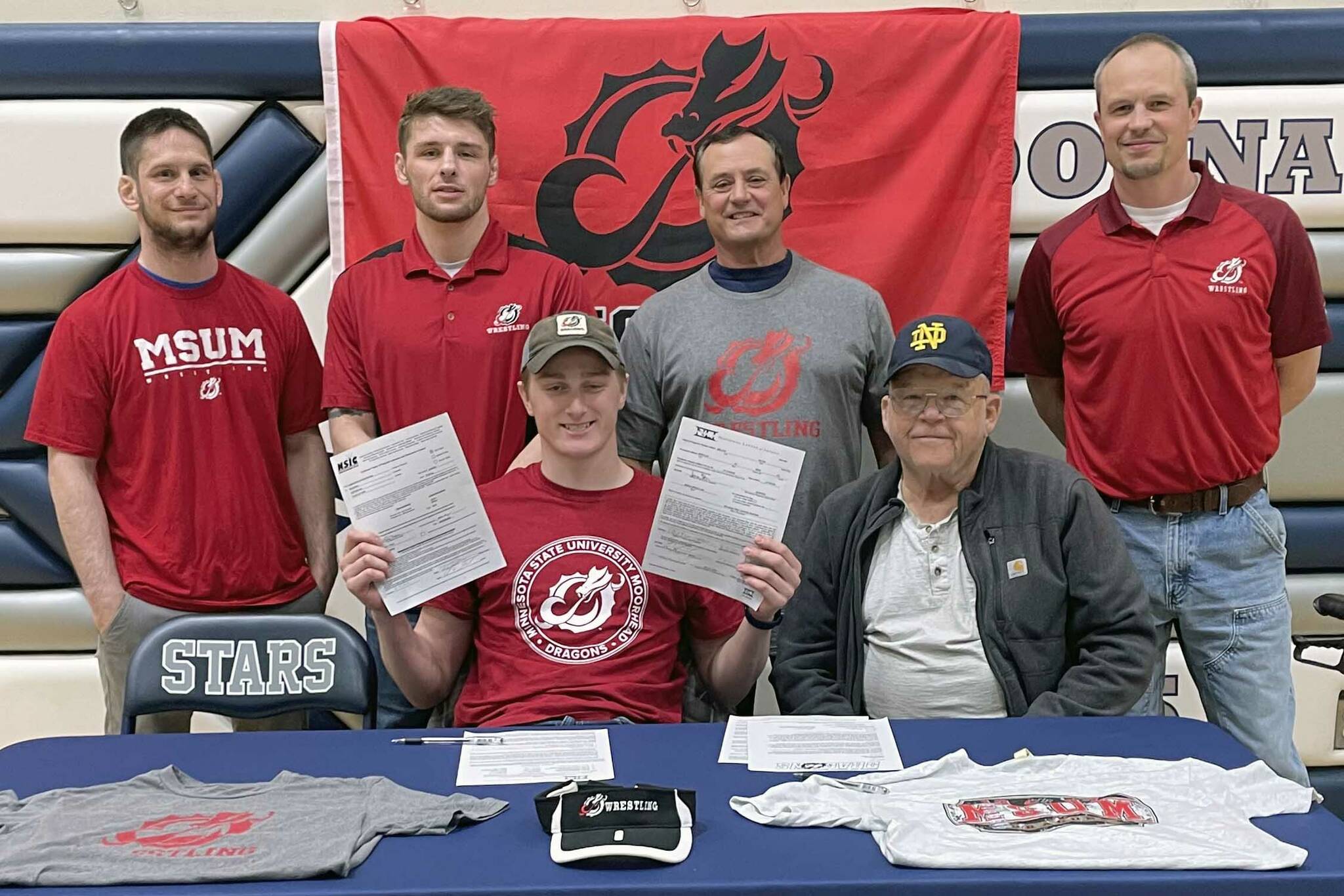 Wayne Mellon, seated at the table with stepfather Michael Gebhard, signs a National Letter of Intent on Tuesday, May 4, 2022, at Soldotna High School in Soldotna, Alaska. In back are SoHi wrestling coaches Aaron Gordon, Logan Parks, Neldon Gardner and Pete Dickinson. (Photo provided)