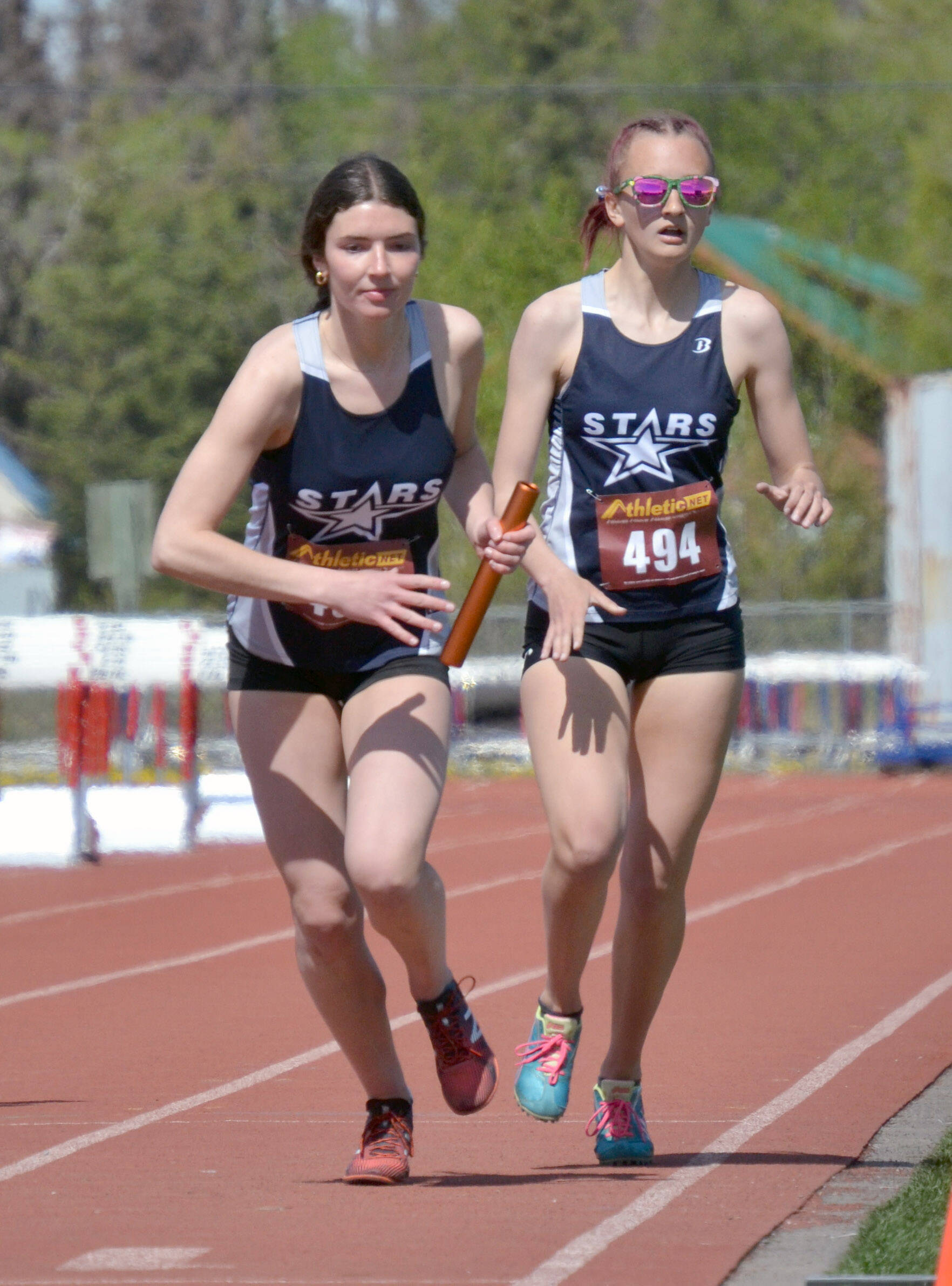 Ellie Burns takes the baton from Jordan Ruffner on the way to Soldotna winning the 3,200-meter relay Saturday, May 21, 2022, at Ed Hollier Field at Kenai Central High School in Kenai, Alaska. (Photo by Jeff Helminiak/Peninsula Clarion)