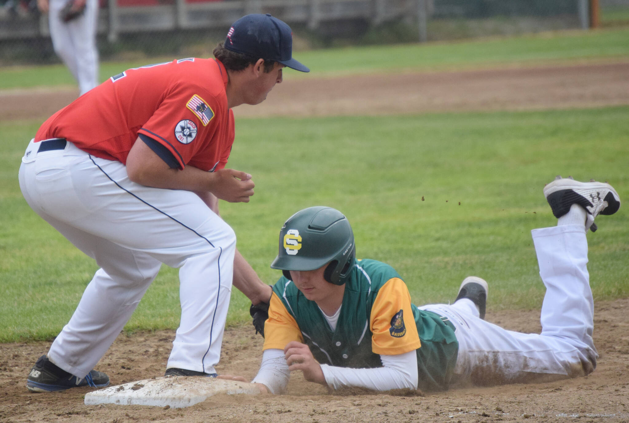 Service’s James Ivey dives under the tag of Post 20 first baseman Riley Johnson on Saturday, June 18, 2022, at Coral Seymour Memorial Park in Kenai, Alaska. (Photo by Jeff Helminiak/Peninsula Clarion)