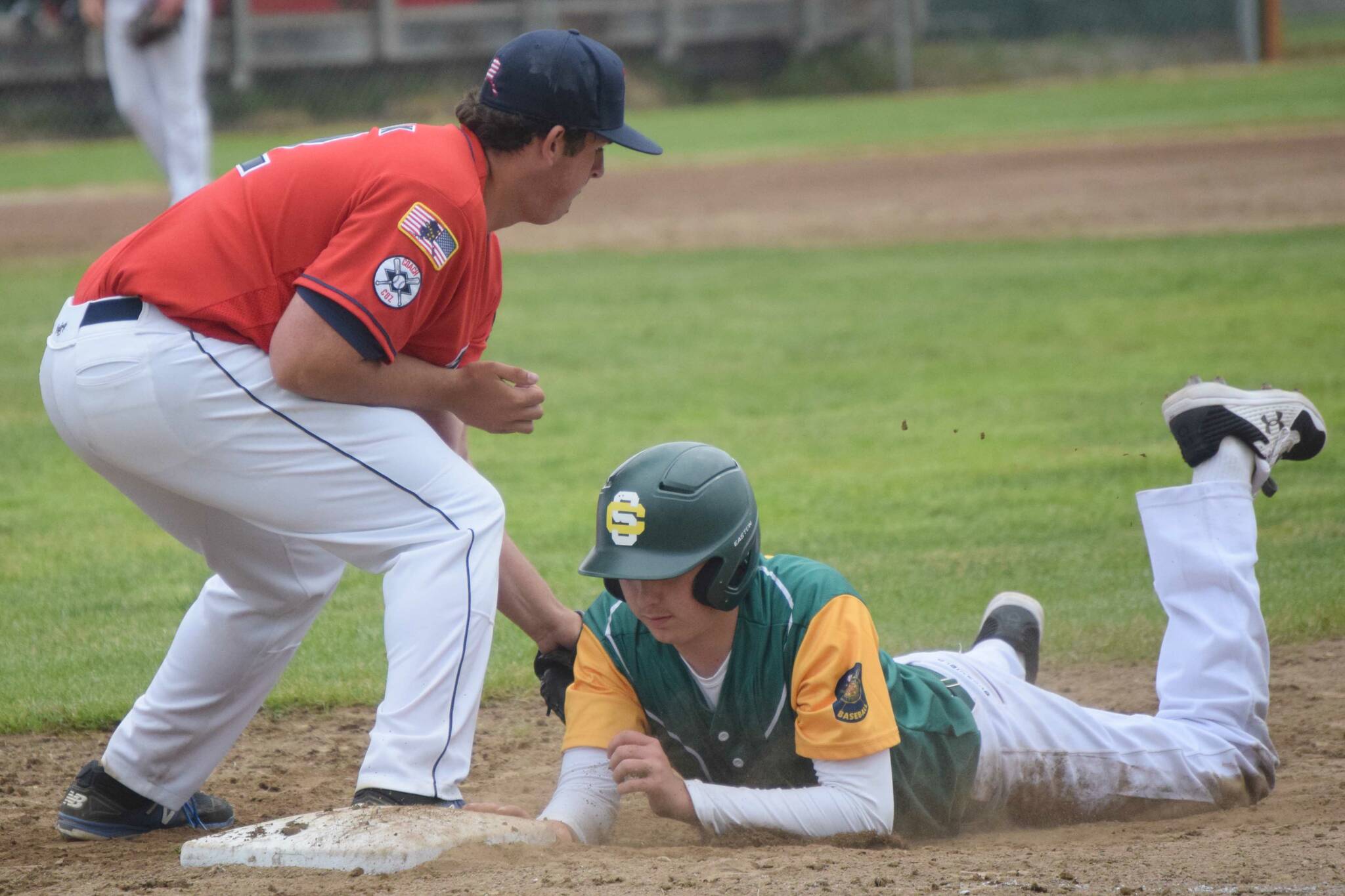 Service's James Ivey dives under the tag of Post 20 first baseman Riley Johnson on Saturday, June 18, 2022, at Coral Seymour Memorial Park in Kenai, Alaska. (Photo by Jeff Helminiak/Peninsula Clarion)