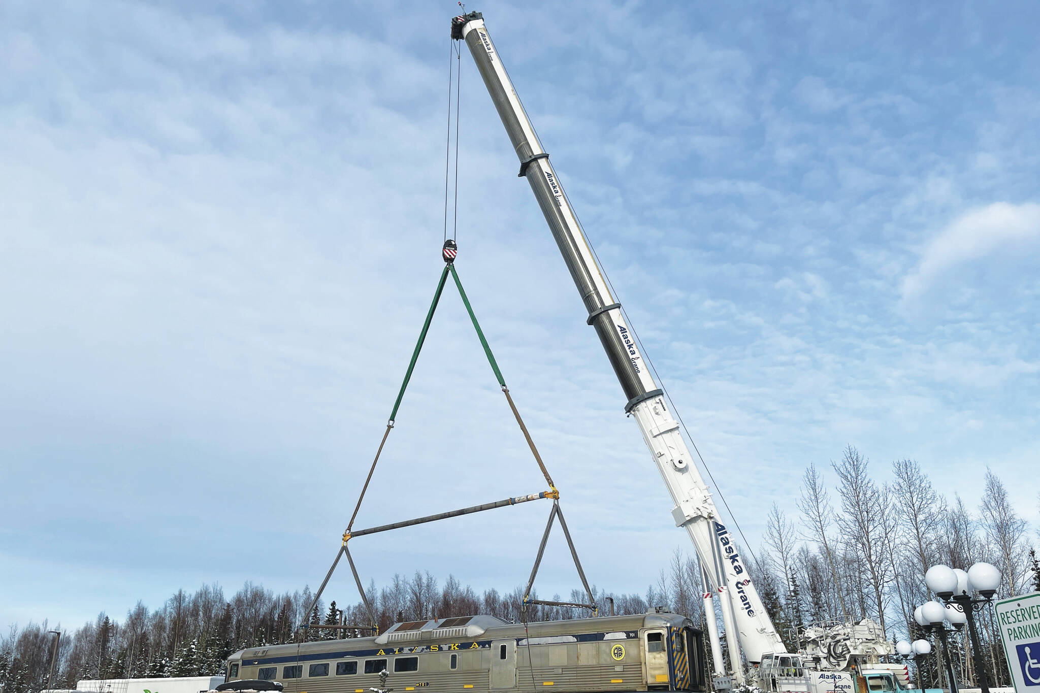 A new train car is hooked to a massive crane in preparation for placement on Whistle Hill in Soldotna, Alaska, on Saturday, Oct. 29, 2022. (Jake Dye/Peninsula Clarion)