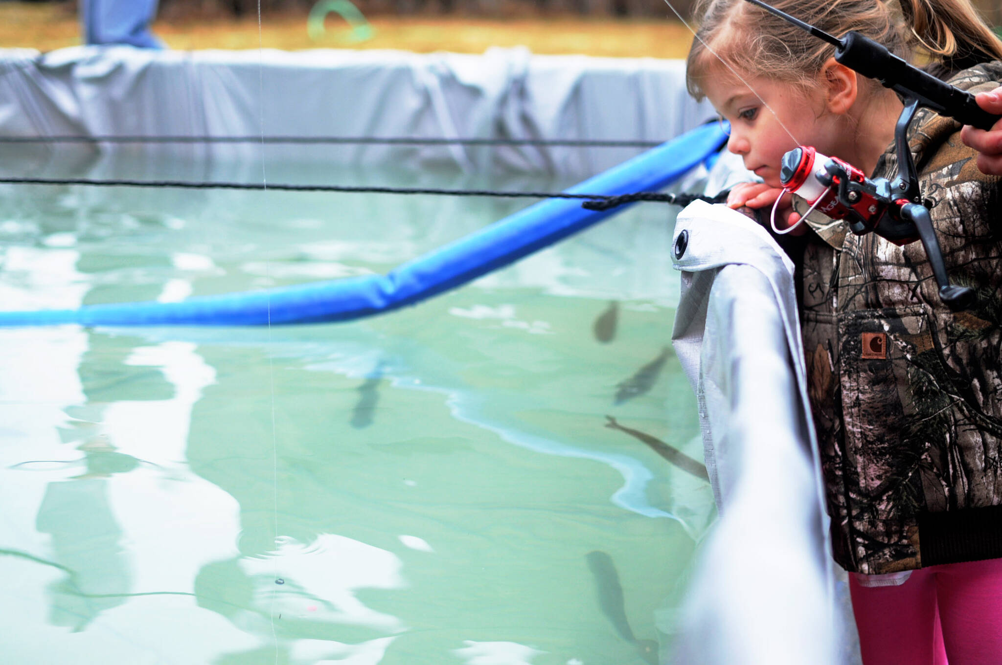 Harper Leck, 3, watches as her line and weight sink into the water at an Alaska Department of Fish and Game-stocked fish pond at the annual Sports and Rec Trade Show at the Soldotna Regional Sports Complex on Sunday, April 29, 2018, in Soldotna, Alaska. (Photo by Elizabeth Earl/Peninsula Clarion file)