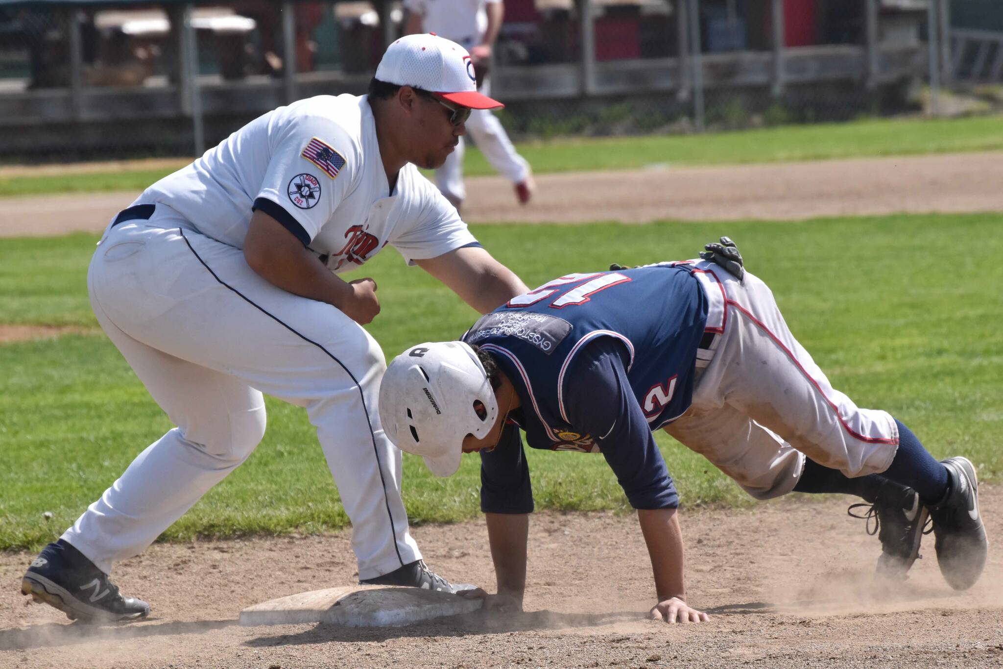 Wasilla Road Warriors' Pedro Camacho slides under the tag of American Legion Twins first baseman Atticus Gibson on Sunday, June 18, 2023, at Coral Seymour Memorial Park in Kenai, Alaska. (Photo by Jeff Helminiak/Peninsula Clarion)