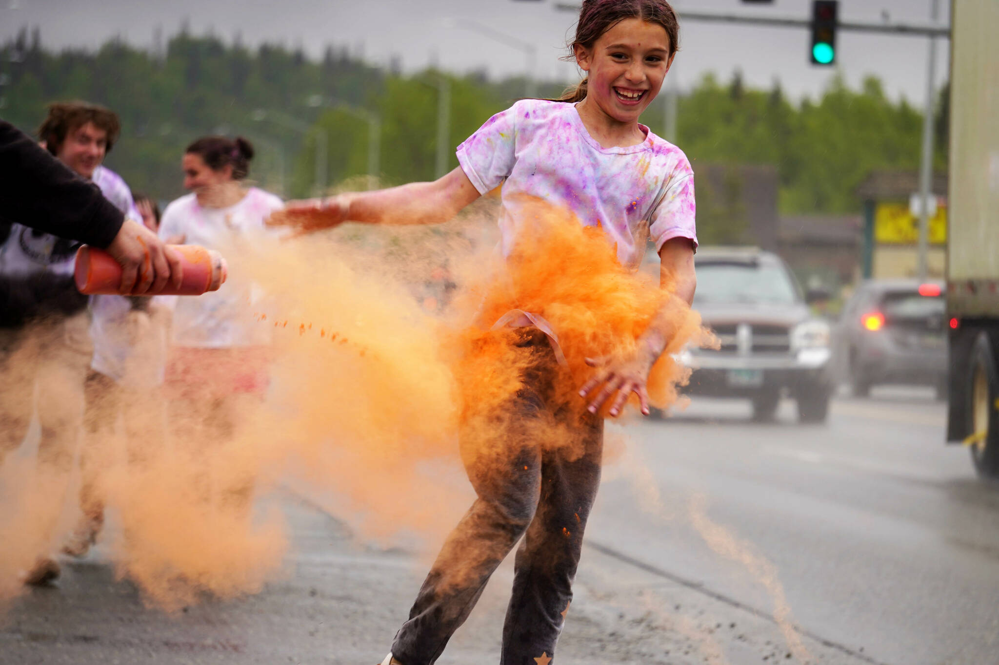 Emily Musgrove emerges from a cloud of orange powder during a color run as part of the opening night of the Levitt AMP Soldotna Music Series along the Sterling Highway in Soldotna, Alaska, on Wednesday, June 5, 2024. (Jake Dye/Peninsula Clarion)