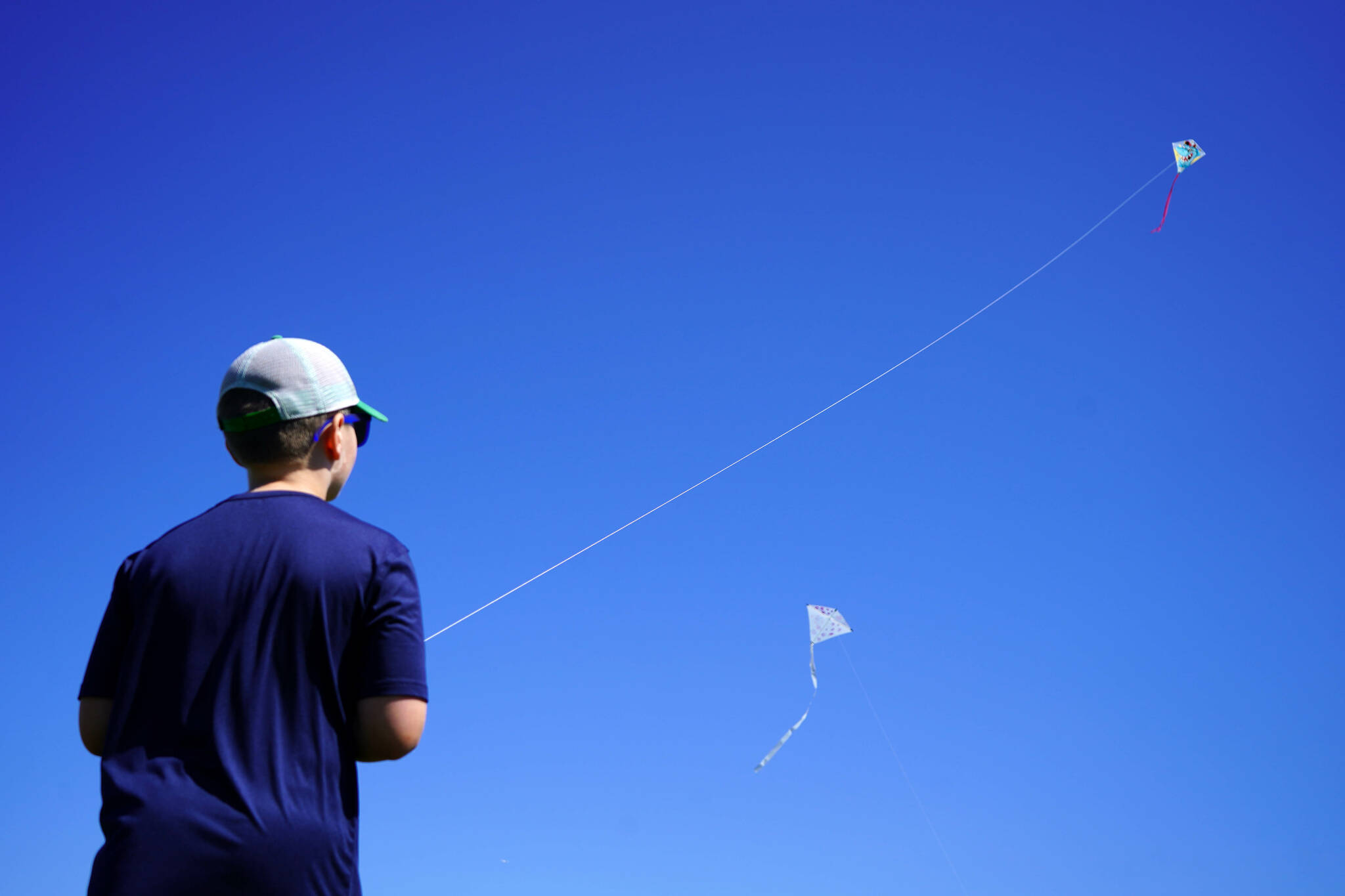 Nathan Nelson directs a kite flying dozens of feet up in the sky above Millennium Square in Kenai, Alaska, during the Kenai Kite Festival on Saturday, June 15, 2024. (Jake Dye/Peninsula Clarion)