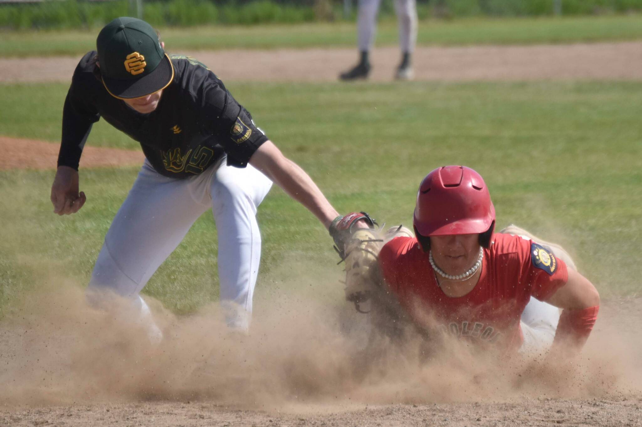 Napoleon (Ohio) River Bandits player Kadyn Radzik dives back into first safely in front of Service first baseman Owen Hickman in the final of the Lance Coz Wood Bat Tournament on Monday, June 24, 2024, at Coral Seymour Memorial Park in Kenai, Alaska. (Photo by Jeff Helminiak/Peninsula Clarion)