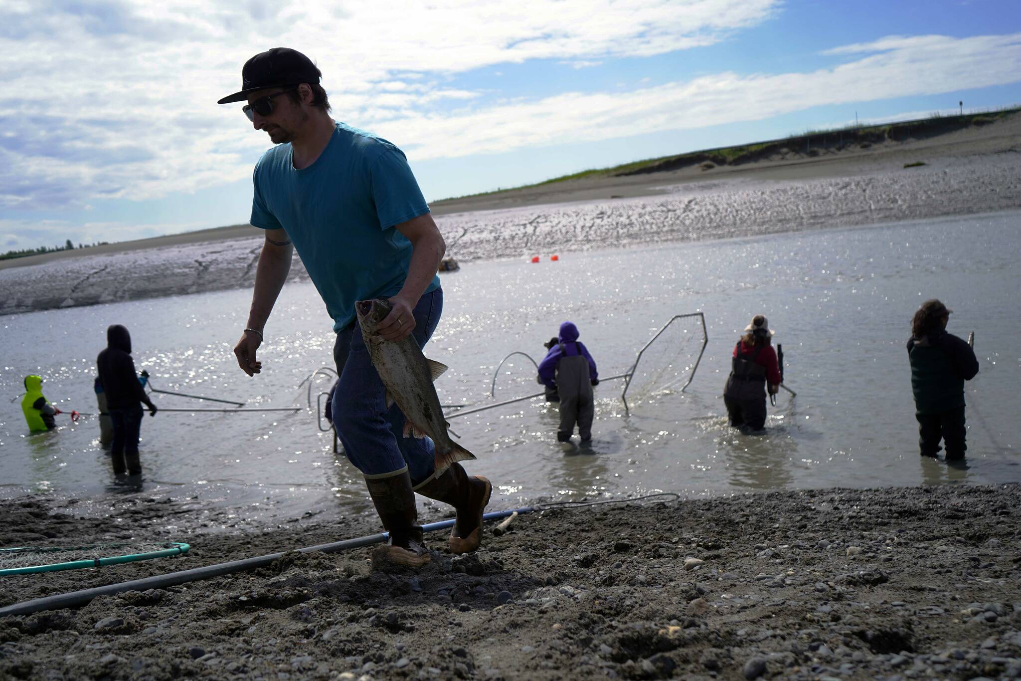 A fisher carries a sockeye salmon away from the water during the opening day of the personal use dipnet fishery at the mouth of the Kasilof River in Alaska, on Tuesday, June 25, 2024. (Jake Dye/Peninsula Clarion)