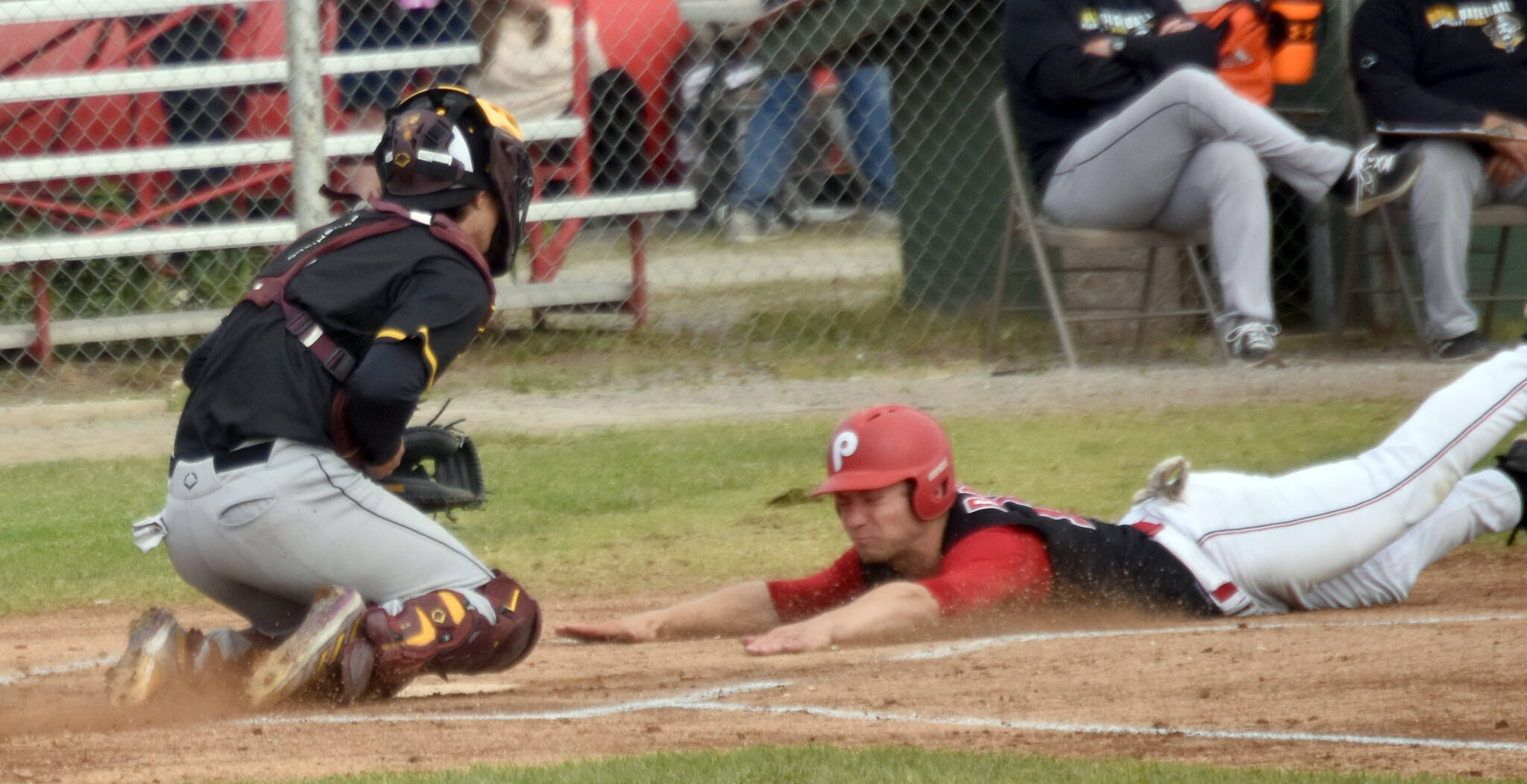 Cole Dawson of the Peninsula Oilers slides into home safely in front of Anchorage Bucs catcher Brody Briggs on Thursday, June 27, 2024, at Coral Seymour Memorial Park in Kenai, Alaska. (Photo by Jeff Helminiak/Peninsula Clarion)