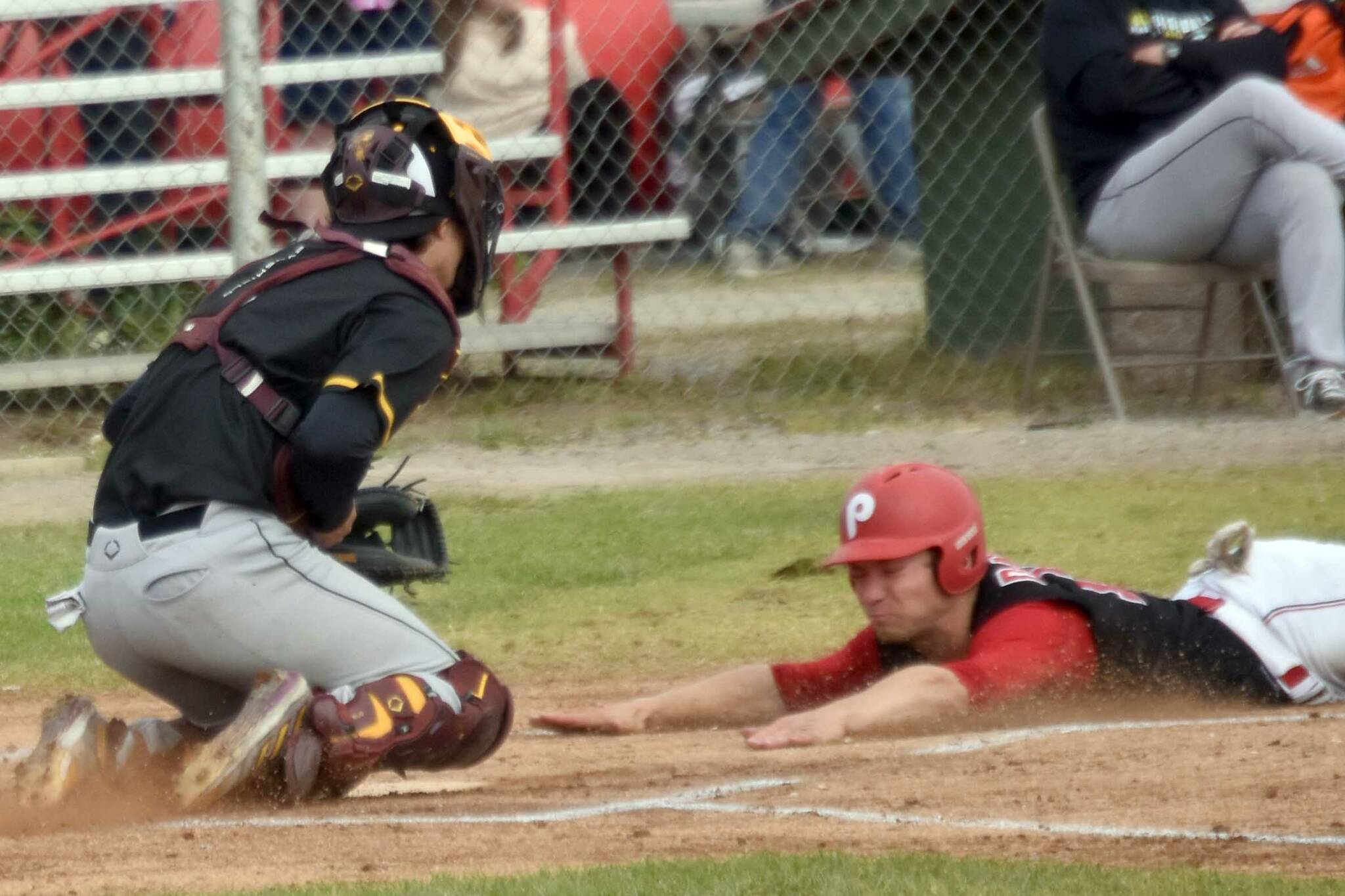 Cole Dawson of the Peninsula Oilers slides into home safely in front of Anchorage Bucs catcher Brody Briggs on Thursday, June 27, 2024, at Coral Seymour Memorial Park in Kenai. (Photo by Jeff Helminiak/Peninsula Clarion)