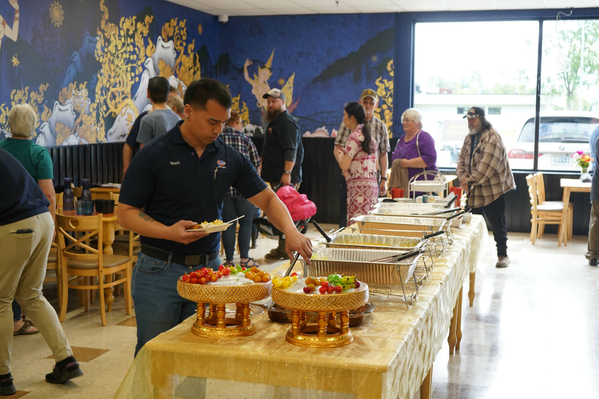 Attendees take food from a buffet during the grand opening of Siam Noodles and Food in Kenai, Alaska, on Tuesday, July 2, 2024. (Jake Dye/Peninsula Clarion)