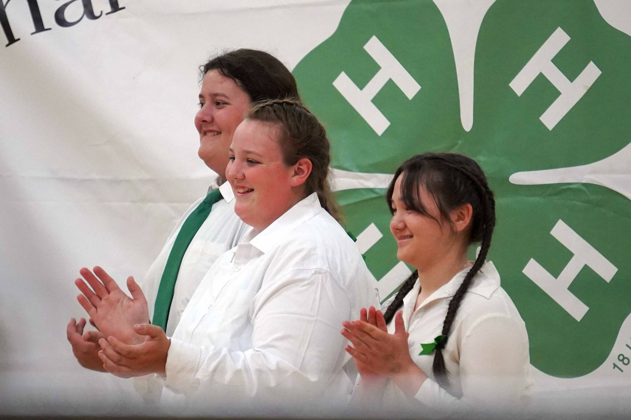 Levi Rankin, Ella Rankin and Xinlan Tanner clap as a fourth member of their quartet, Xiling Tanner, shows a community service turkey they raised for auction during the Kenai Peninsula District 4-H Agriculture Expo in the Soldotna Regional Sports Complex in Soldotna, Alaska, on Saturday, July 27, 2024. (Jake Dye/Peninsula Clarion)