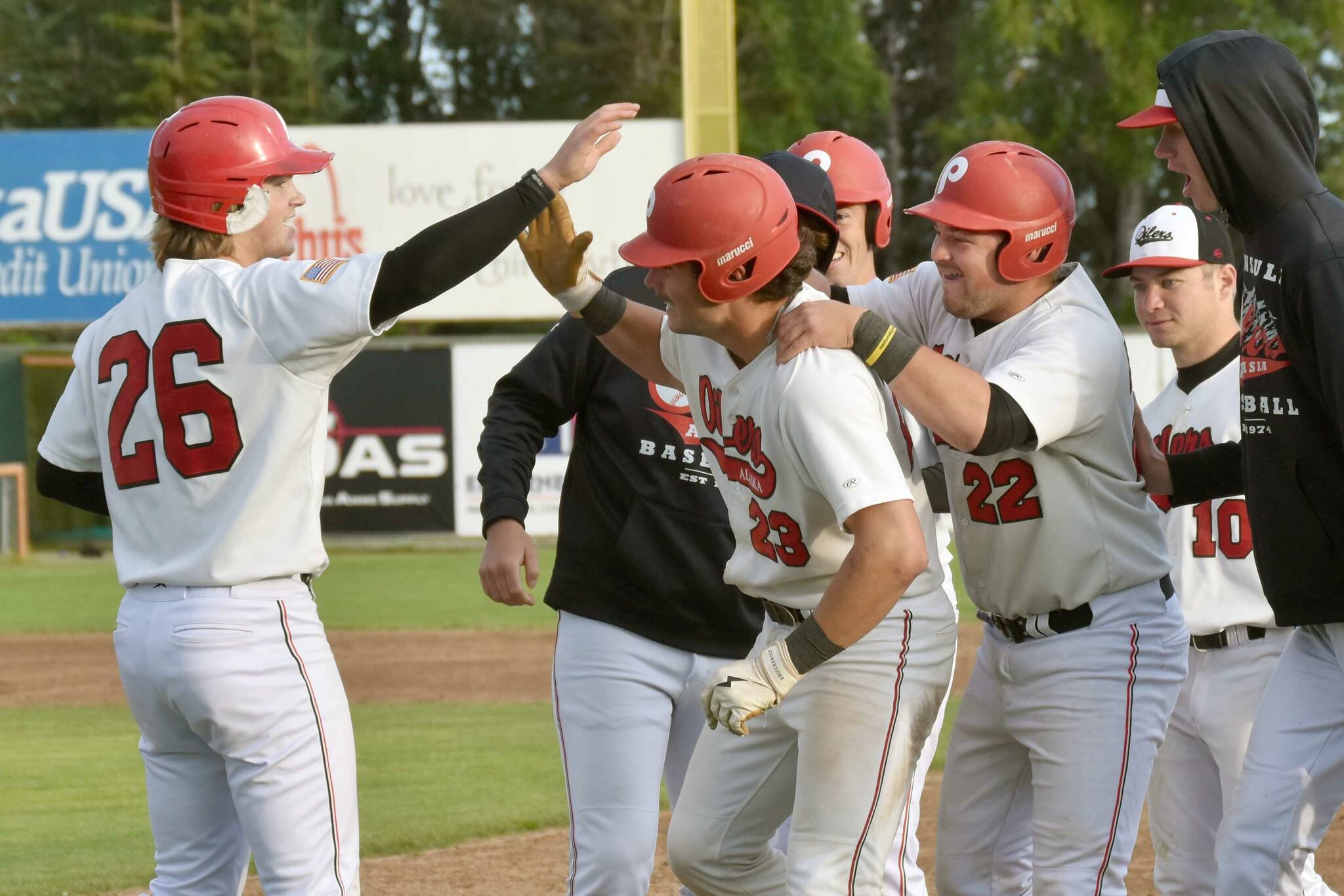 Peninsula Oilers catcher Braden Smith (23) gets congratulations from Cody New (26) on Monday, July 29, 2024, at Coral Seymour Memorial Park in Kenai, Alaska. Smith drove in New for the game-winning run in the bottom of the 10th inning. (Photo by Jeff Helminiak/Peninsula Clarion)